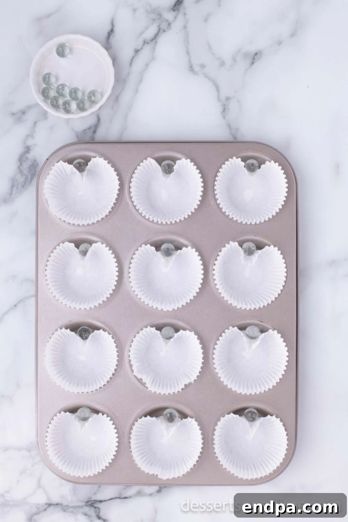 Cupid's Cupcakes 4 Muffin tin lined with cupcake liners, each with a marble placed to create a heart shape.