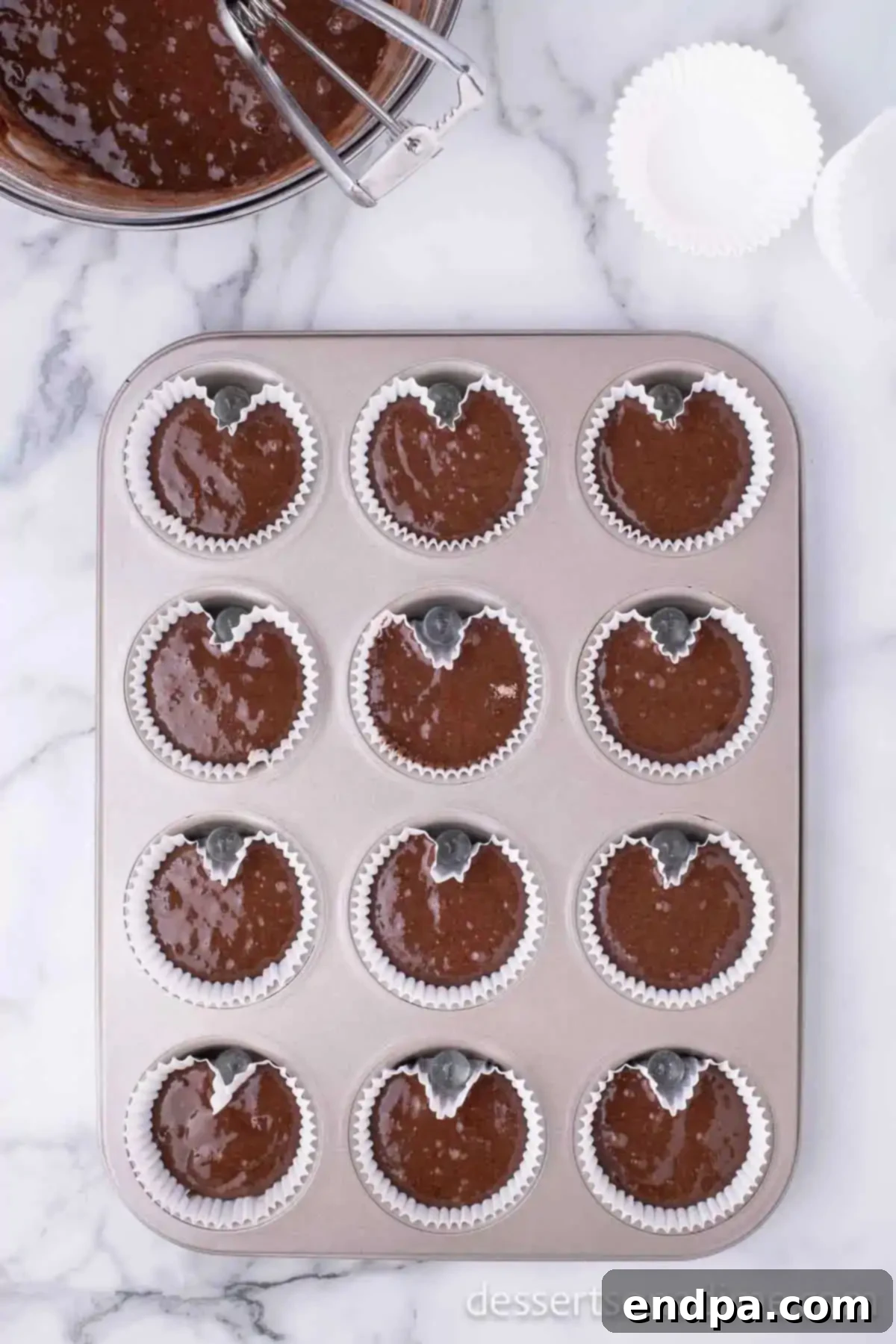 Cupid's Cupcakes 5 Cupcake batter poured into heart-shaped liners in a muffin tin.