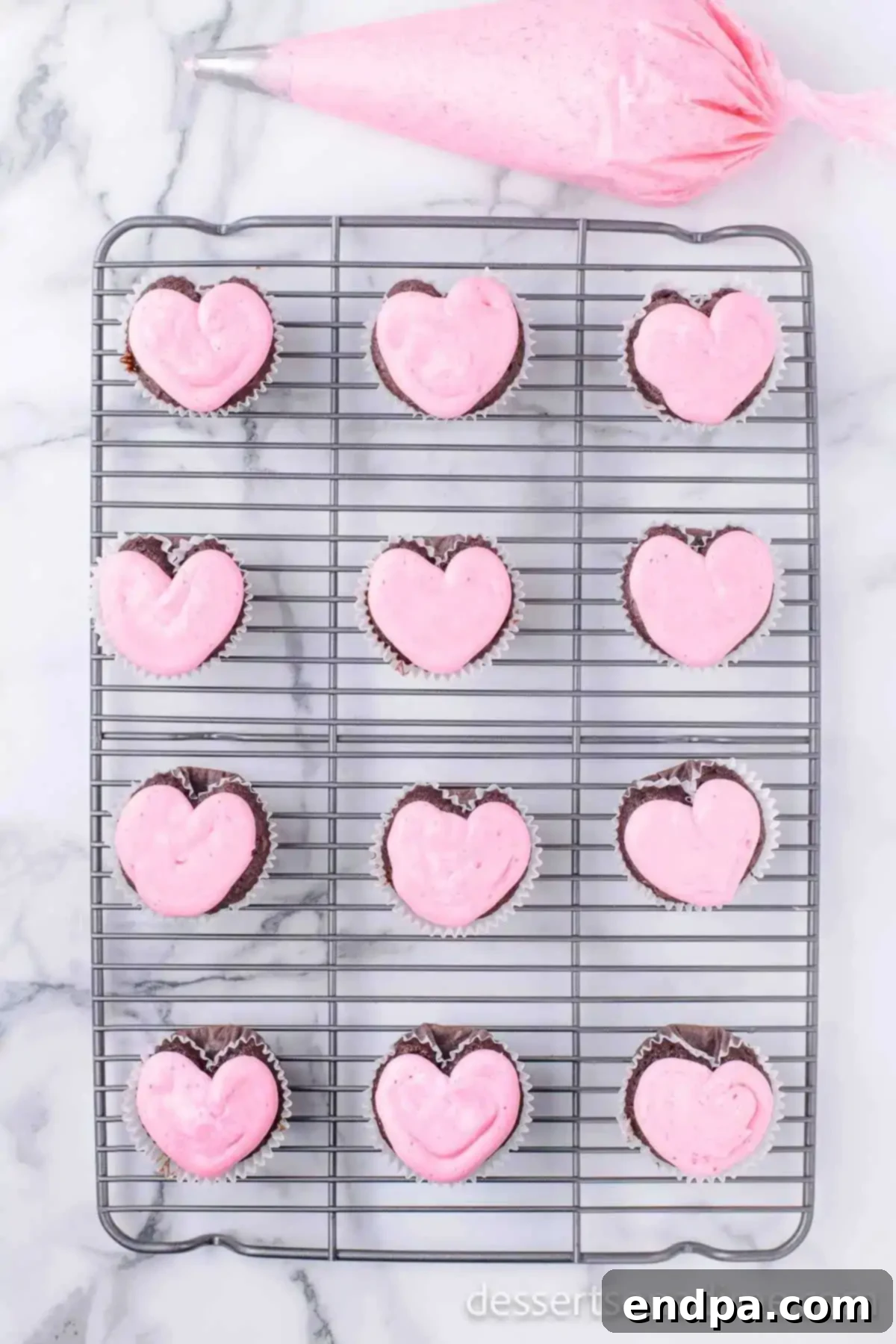 Cupid's Cupcakes 10 Pink icing being piped onto cooled heart-shaped cupcakes.