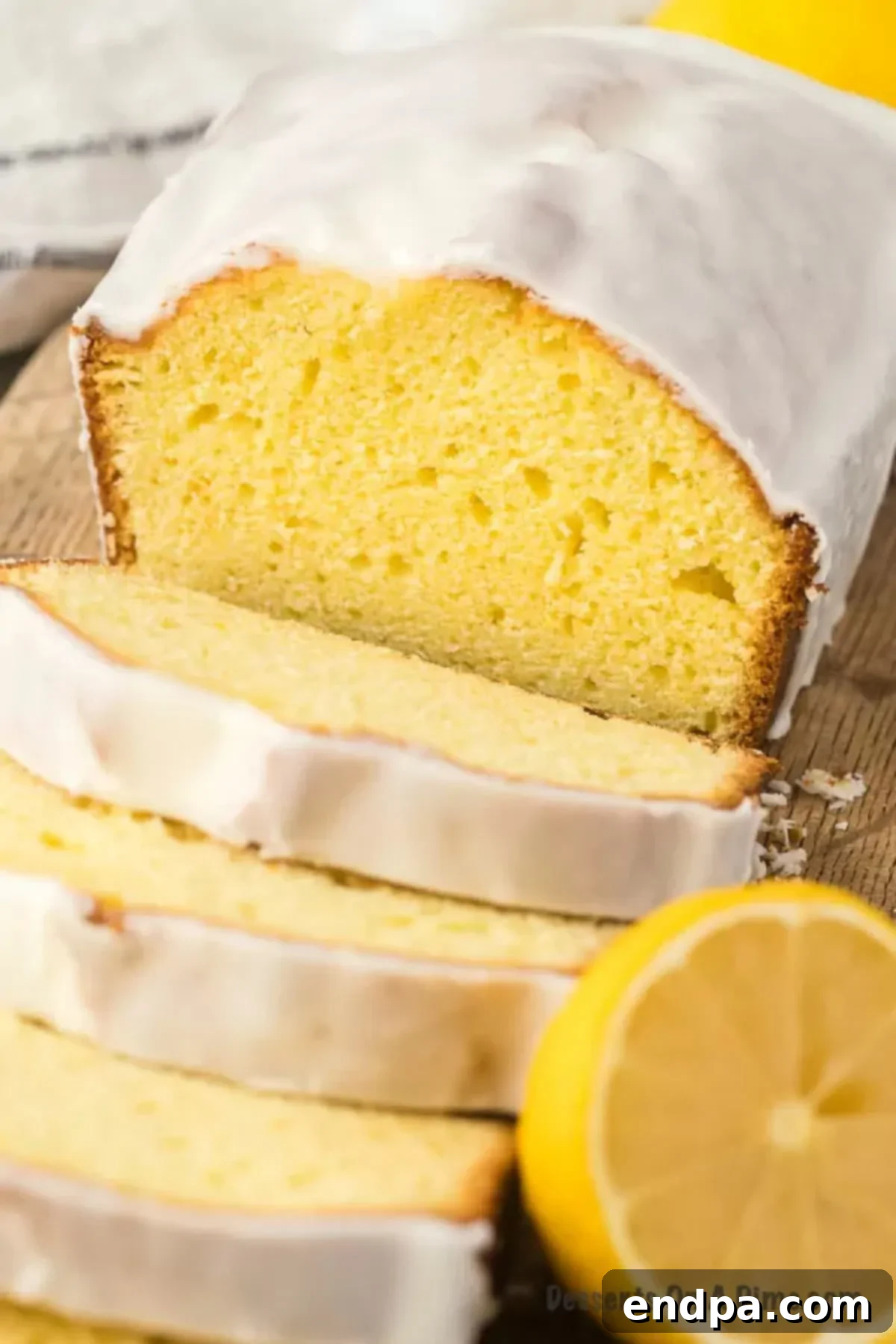 Starbucks Famous Lemon Loaf At Home 10 Close up image of a slice of moist lemon loaf on a cutting board, garnished with a fresh lemon wedge.