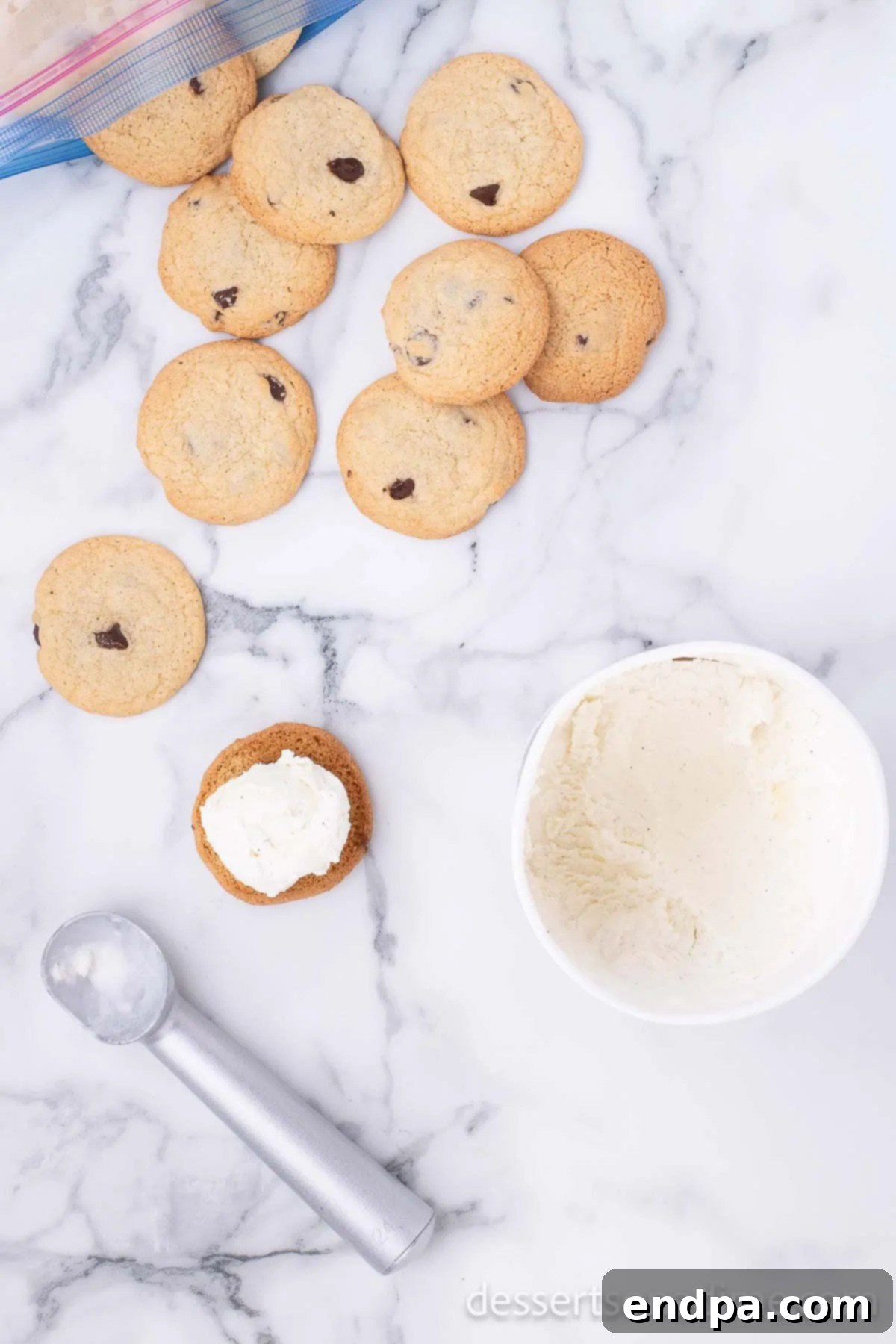 A scoop of vanilla ice cream being placed onto a chilled chocolate chip cookie, preparing the base for the Chipwich sandwich.