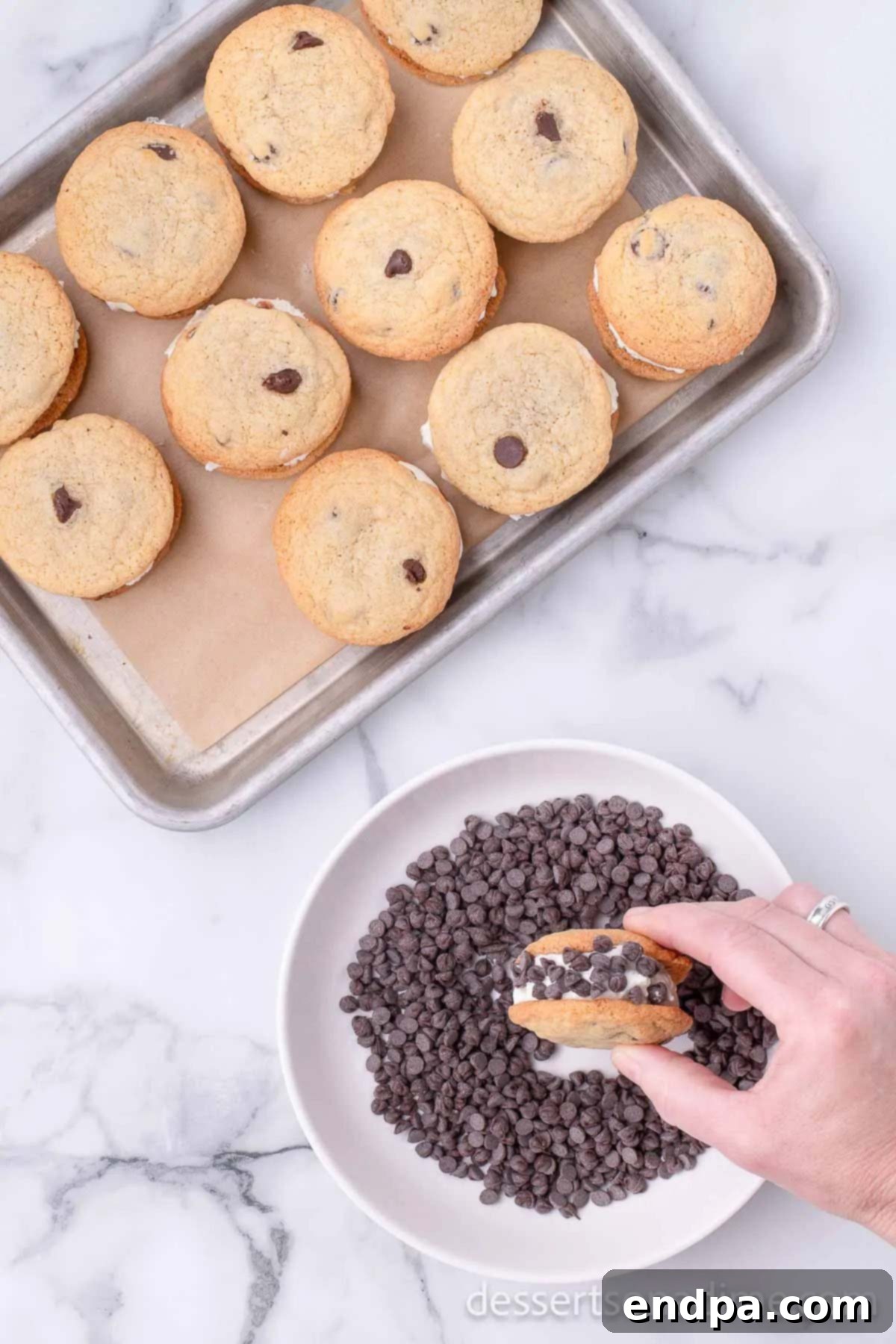A freshly assembled Chipwich ice cream sandwich being rolled in a bowl of mini chocolate chips, ensuring a complete coating around the edges.