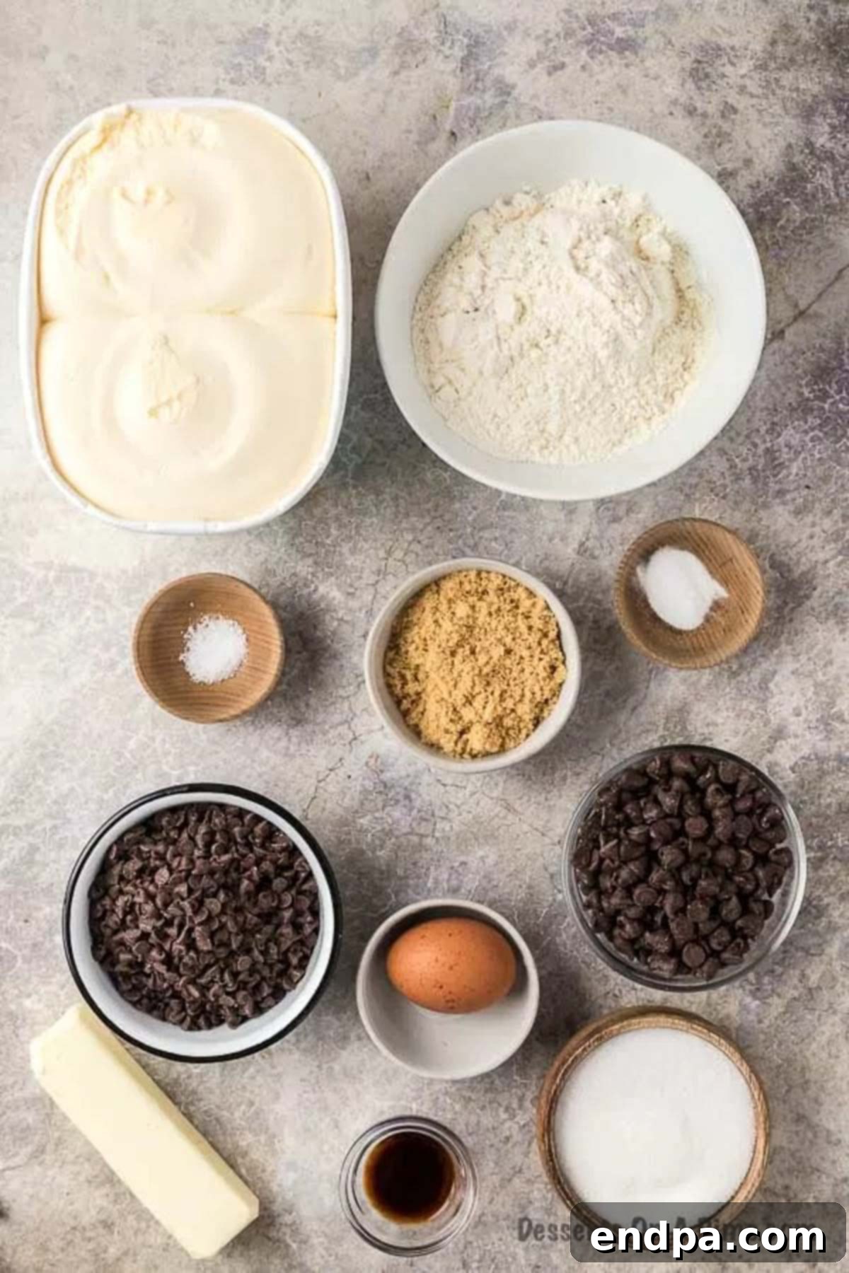 Assorted ingredients laid out for making Chipwich cookies and sandwiches, including butter, sugars, flour, eggs, vanilla, chocolate chips, and a tub of vanilla ice cream.