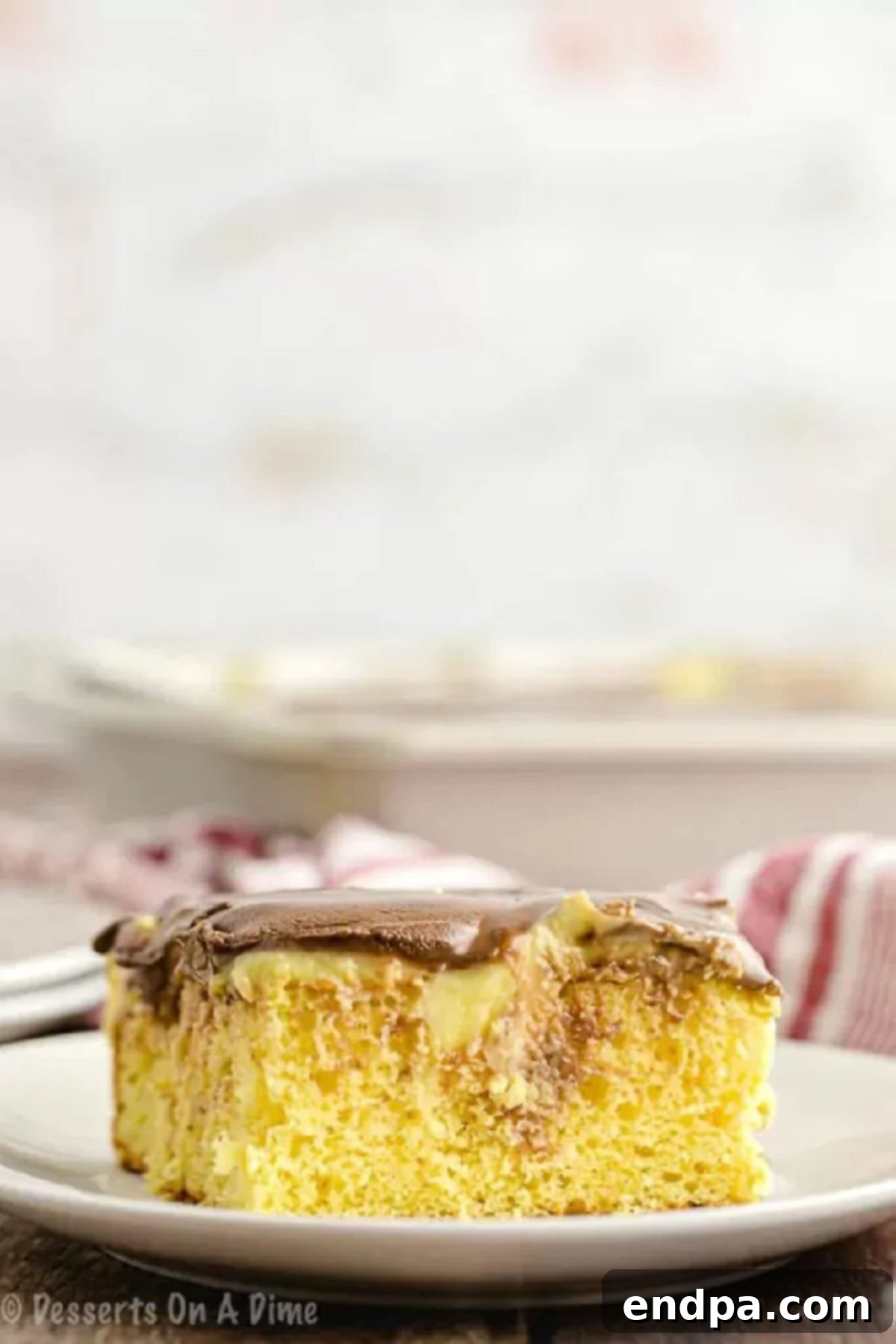 A slice of the Boston Cream Poke Cake on a white serving plate.  