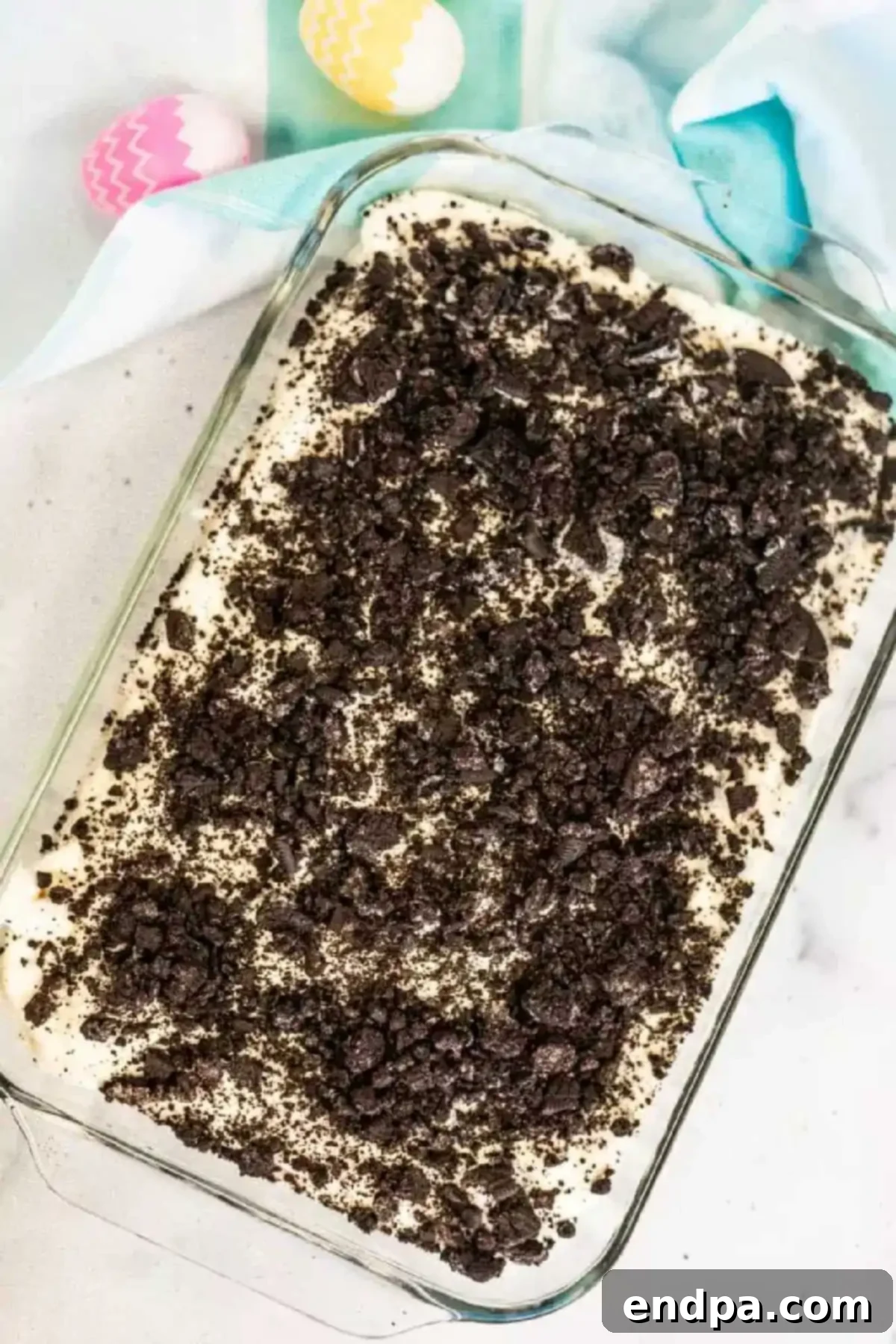 Spring Garden Dirt Cake 6 The creamy filling being spread evenly over the crushed Oreo base in the baking pan.