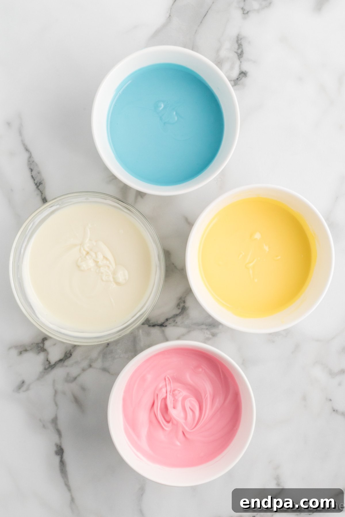Bowls with melted pink, blue, yellow candy coating and white chocolate.
