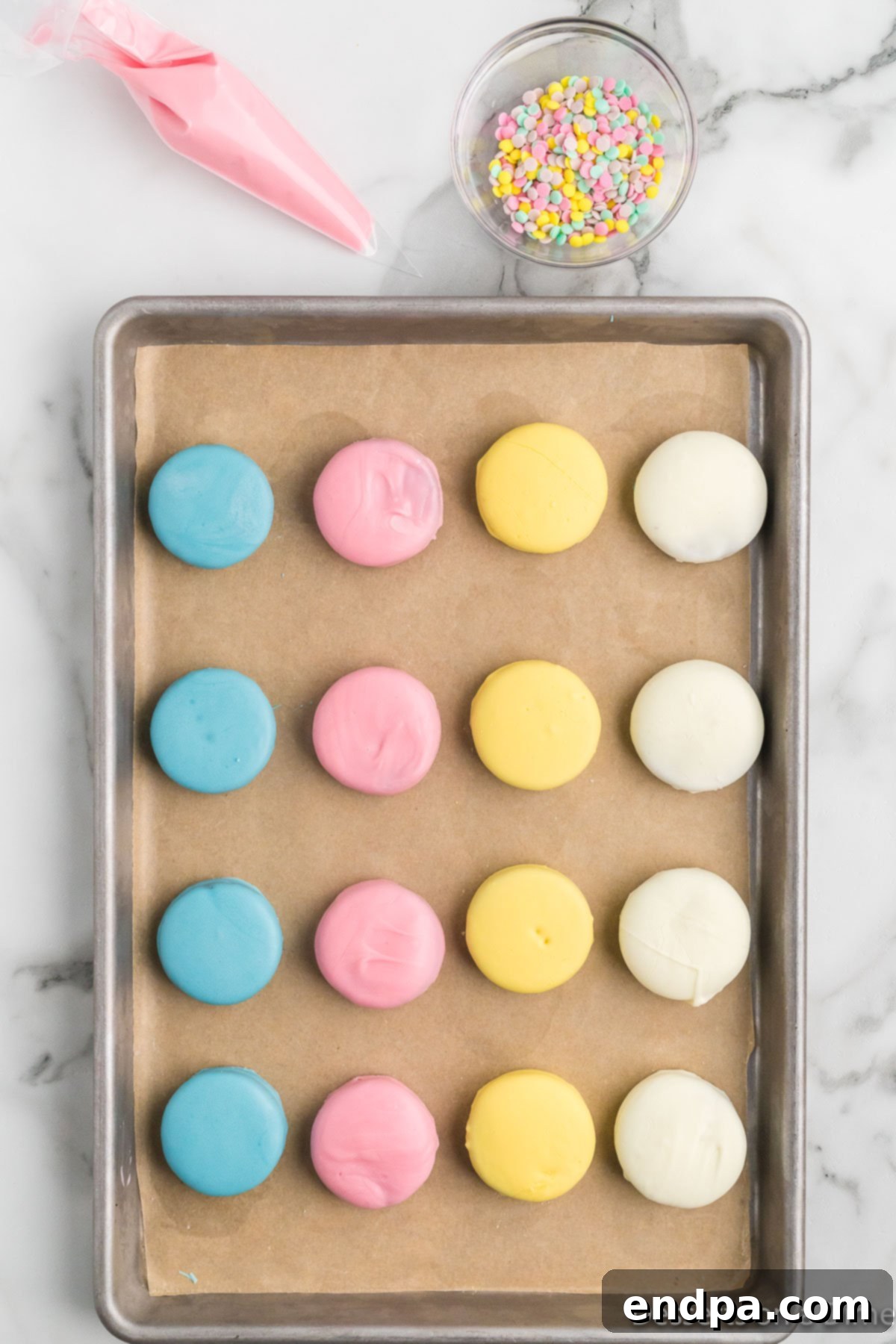 Coated Oreo cookies drying in a single layer on a baking sheet lined with parchment paper.
