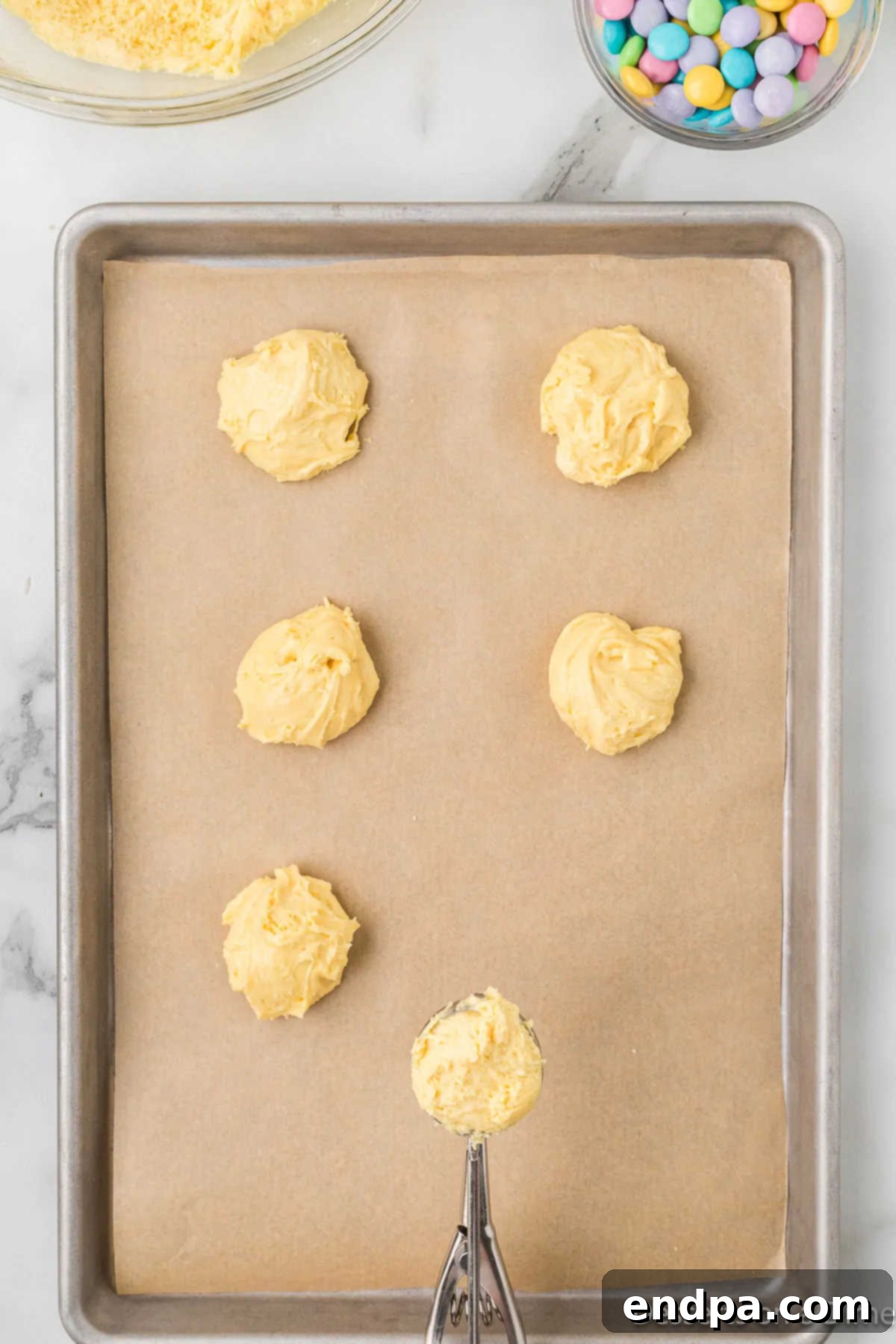 Scooped cookie dough balls placed on a parchment-lined baking sheet.