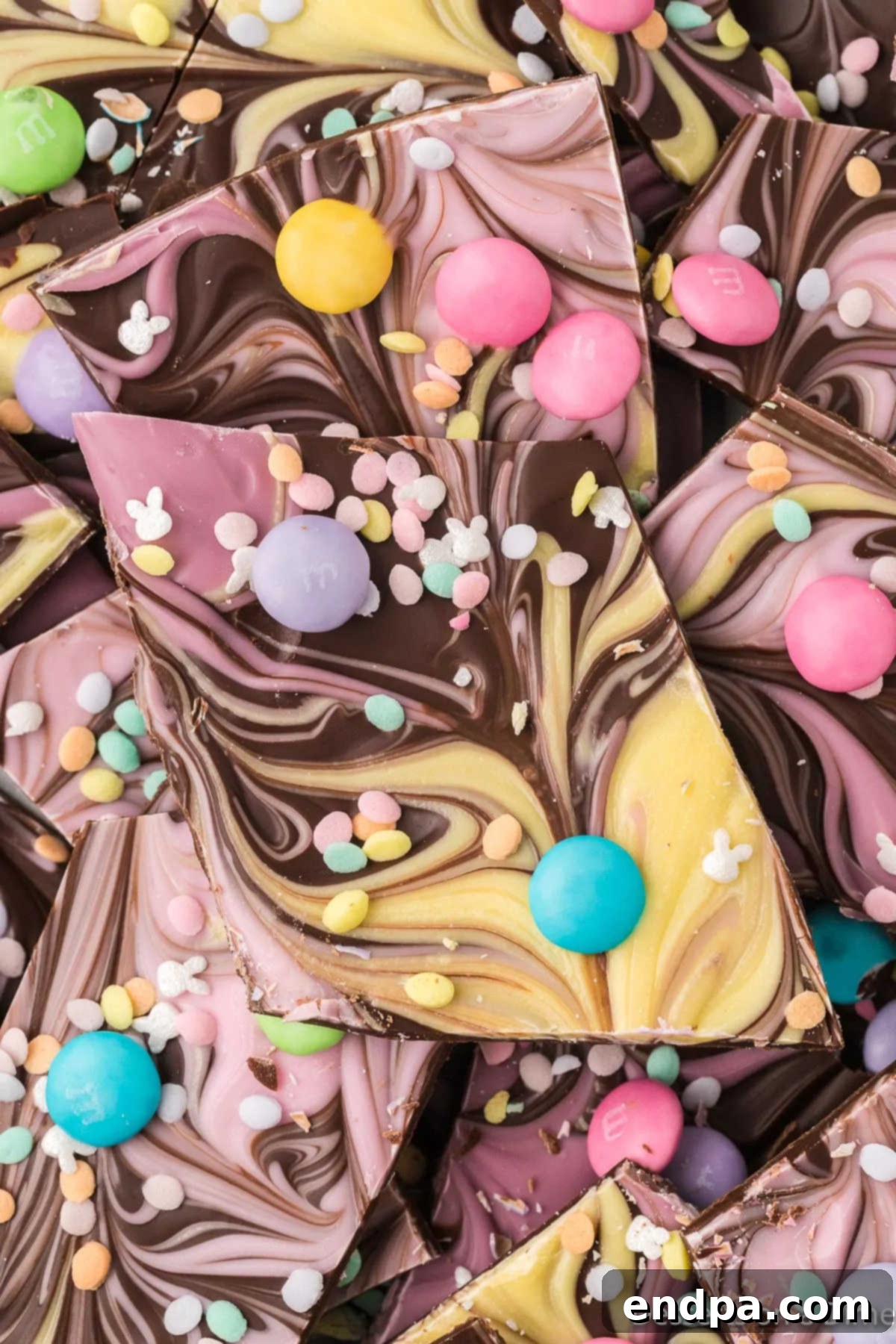 Broken pieces of homemade Easter chocolate bark arranged on a platter, showcasing the colorful swirls and festive toppings.