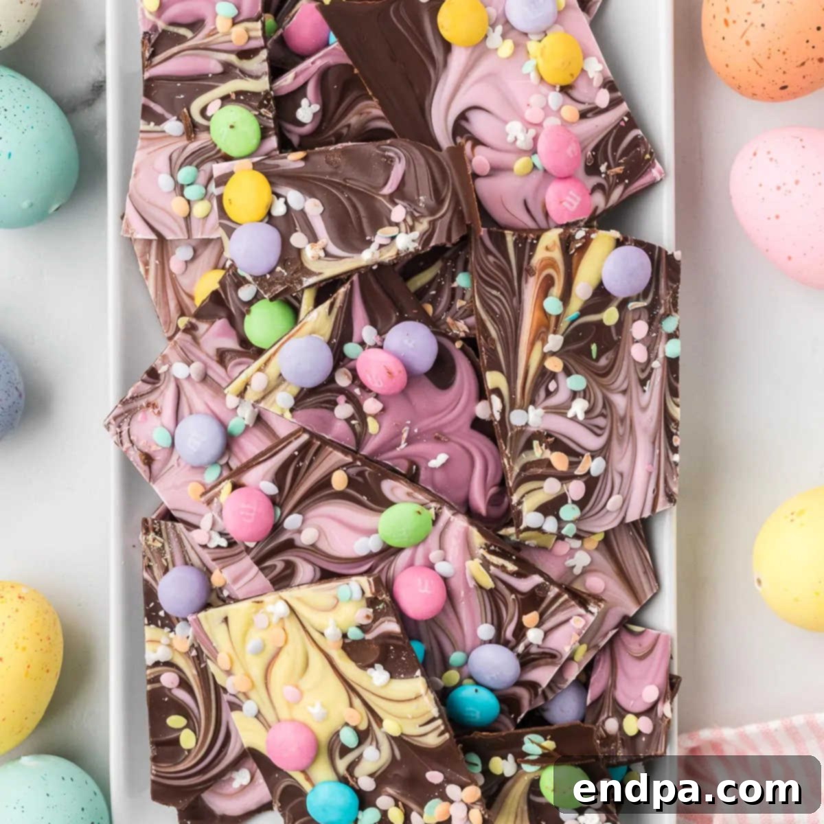 A square image of the finished Easter Chocolate Bark, showing swirls of pastel chocolate and scattered candies.
