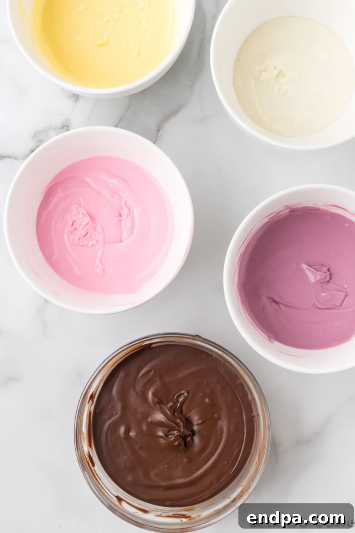 Melted semi-sweet chocolate, white chocolate, and colored candy melts in separate bowls.