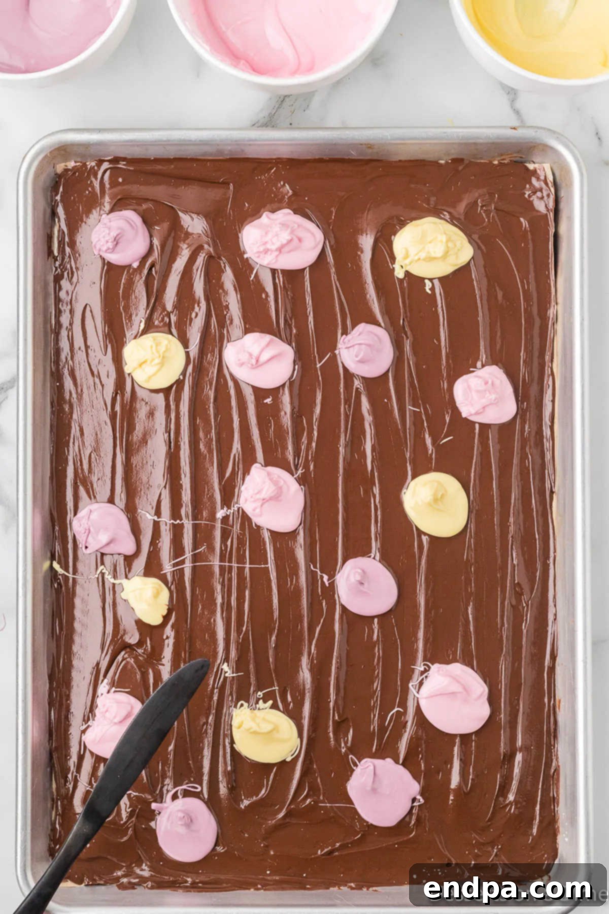 Dollops of pink, purple, and yellow pastel candy melts dropped onto the dark chocolate base.