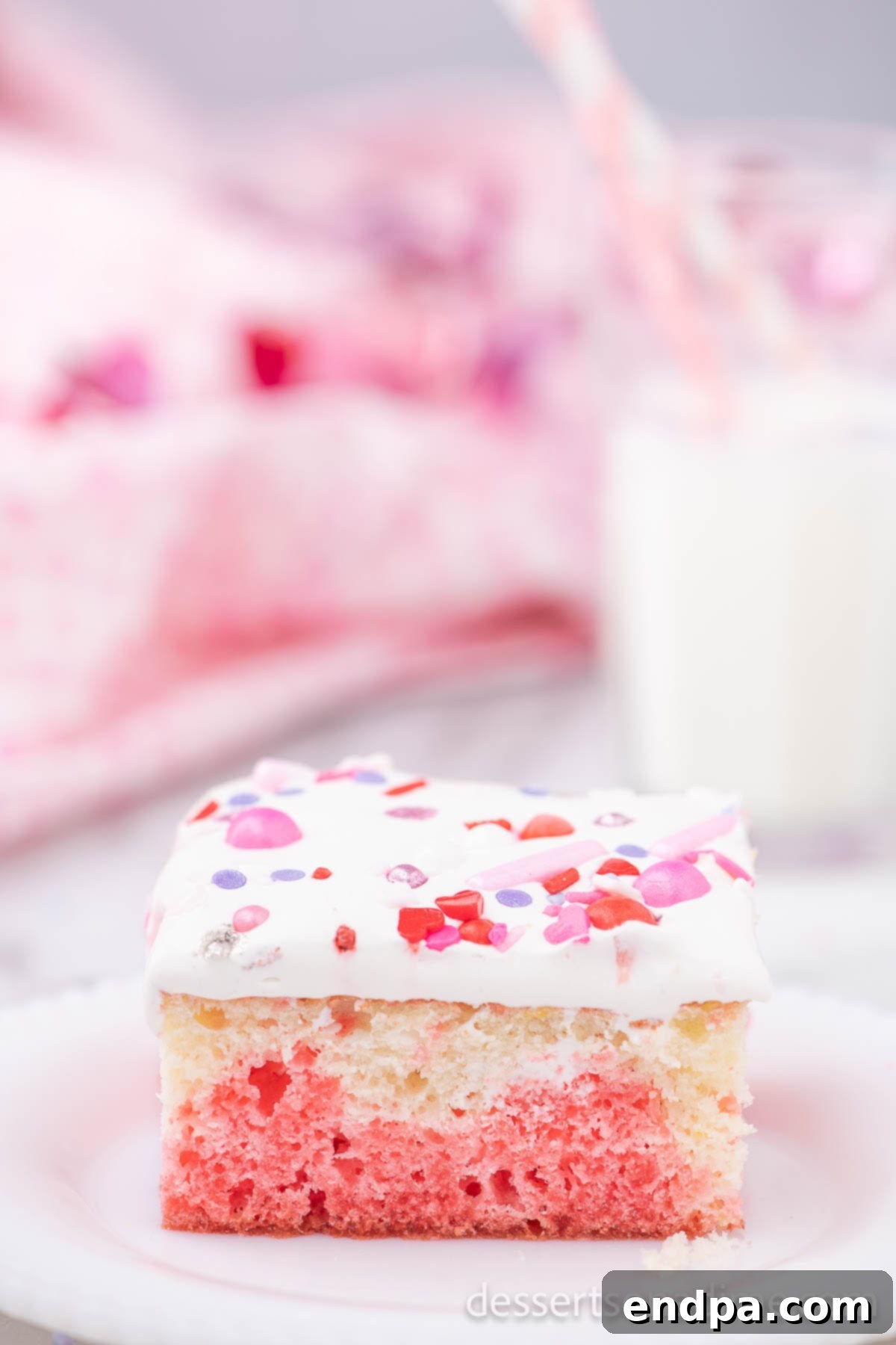 Romantic Valentines Poke Cake 2 Slice of Valentine's Day Poke Cake on plate, showcasing its vibrant layers and festive sprinkles.