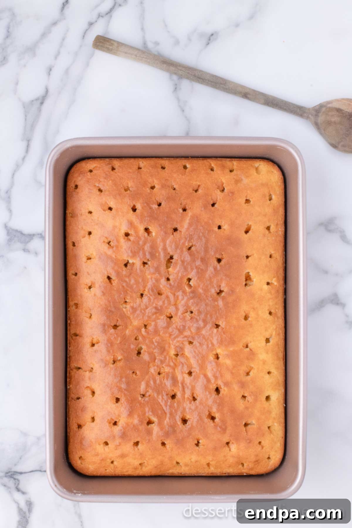 Romantic Valentines Poke Cake 5 Freshly baked cake with holes poked evenly across its surface.
