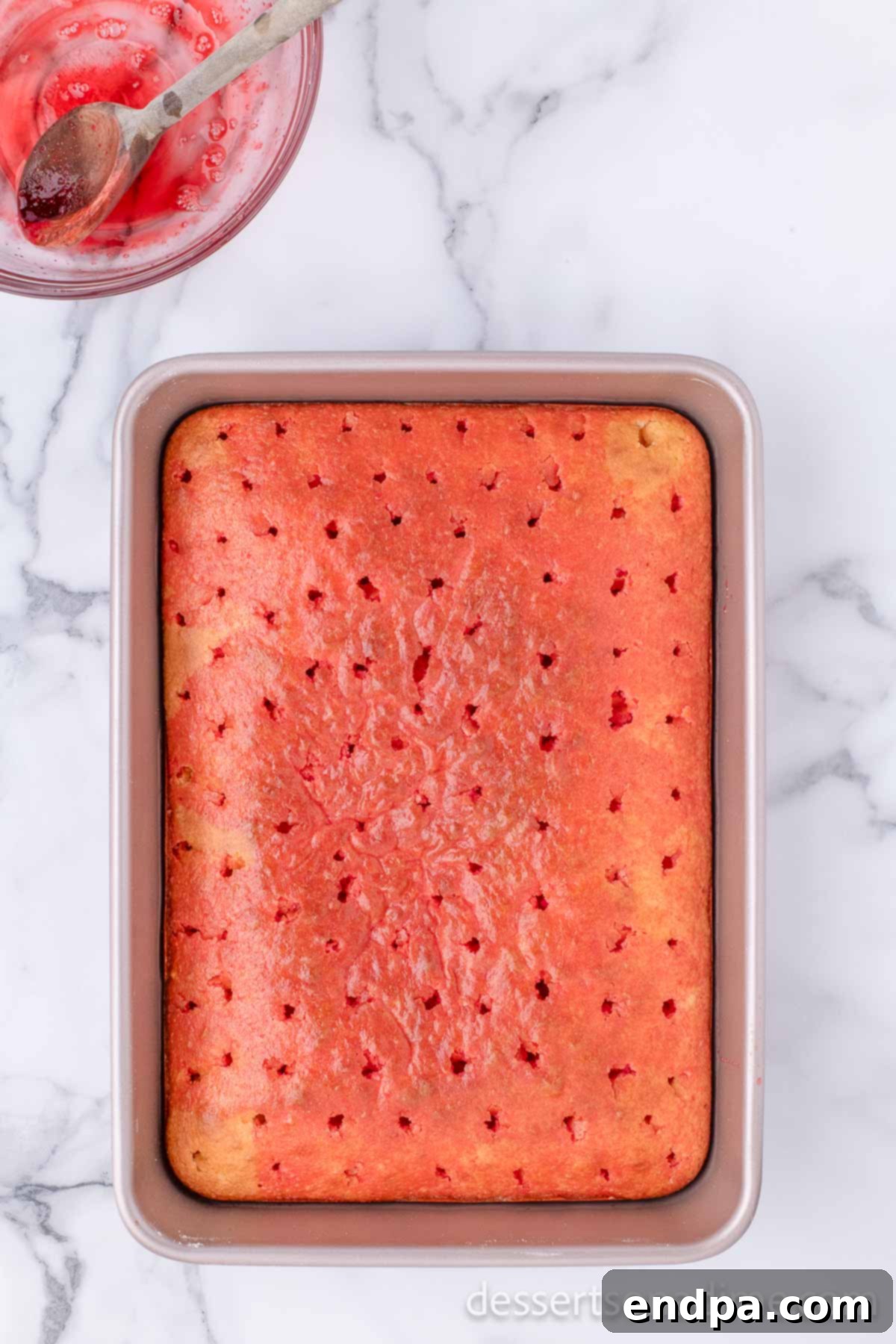 Romantic Valentines Poke Cake 6 Strawberry jello mixture being spooned over the poked cake.