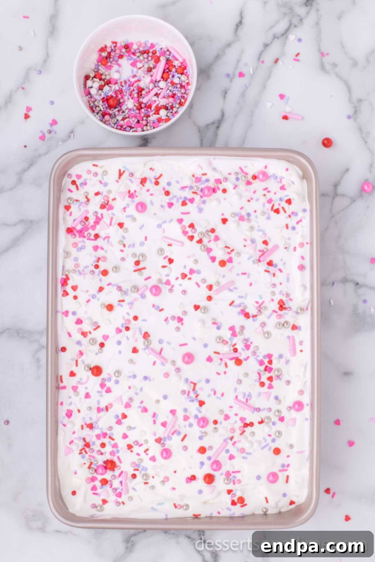 Romantic Valentines Poke Cake 7 Finished Valentine's Day Poke Cake topped with whipped topping and colorful sprinkles.