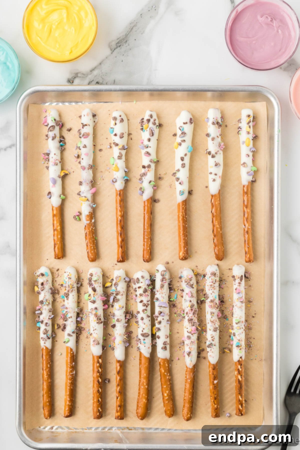 Crushed candy added to pretzels on baking sheet. 