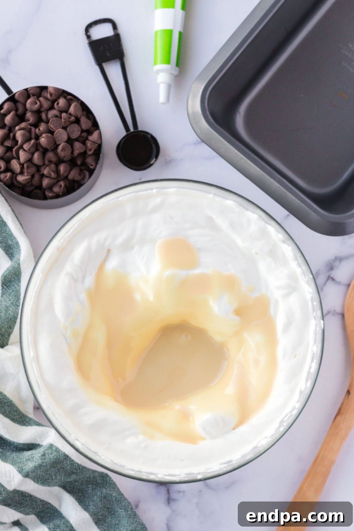 Mixing bowl with heavy cream and sweetened condensed milk being whipped.