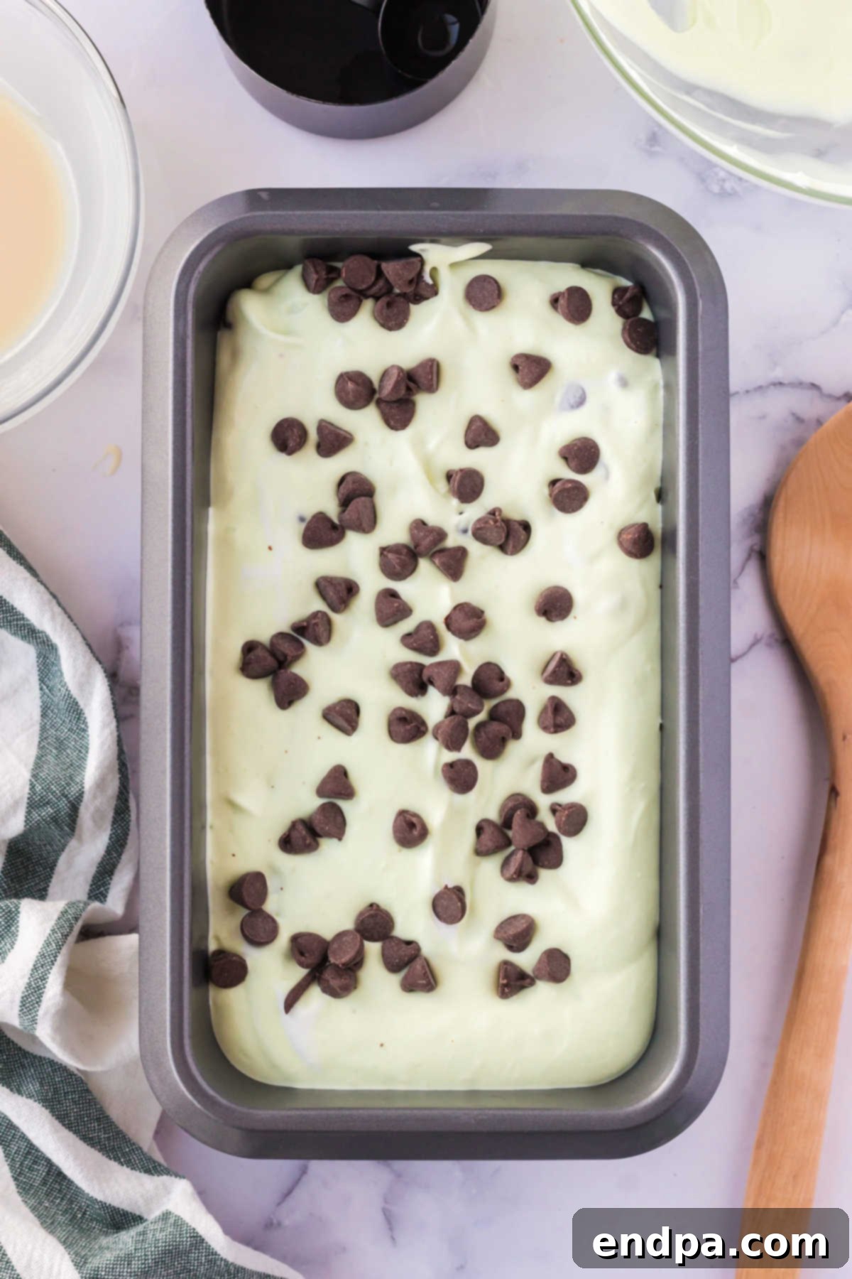 Mint chocolate chip ice cream mixture spread into a loaf pan.