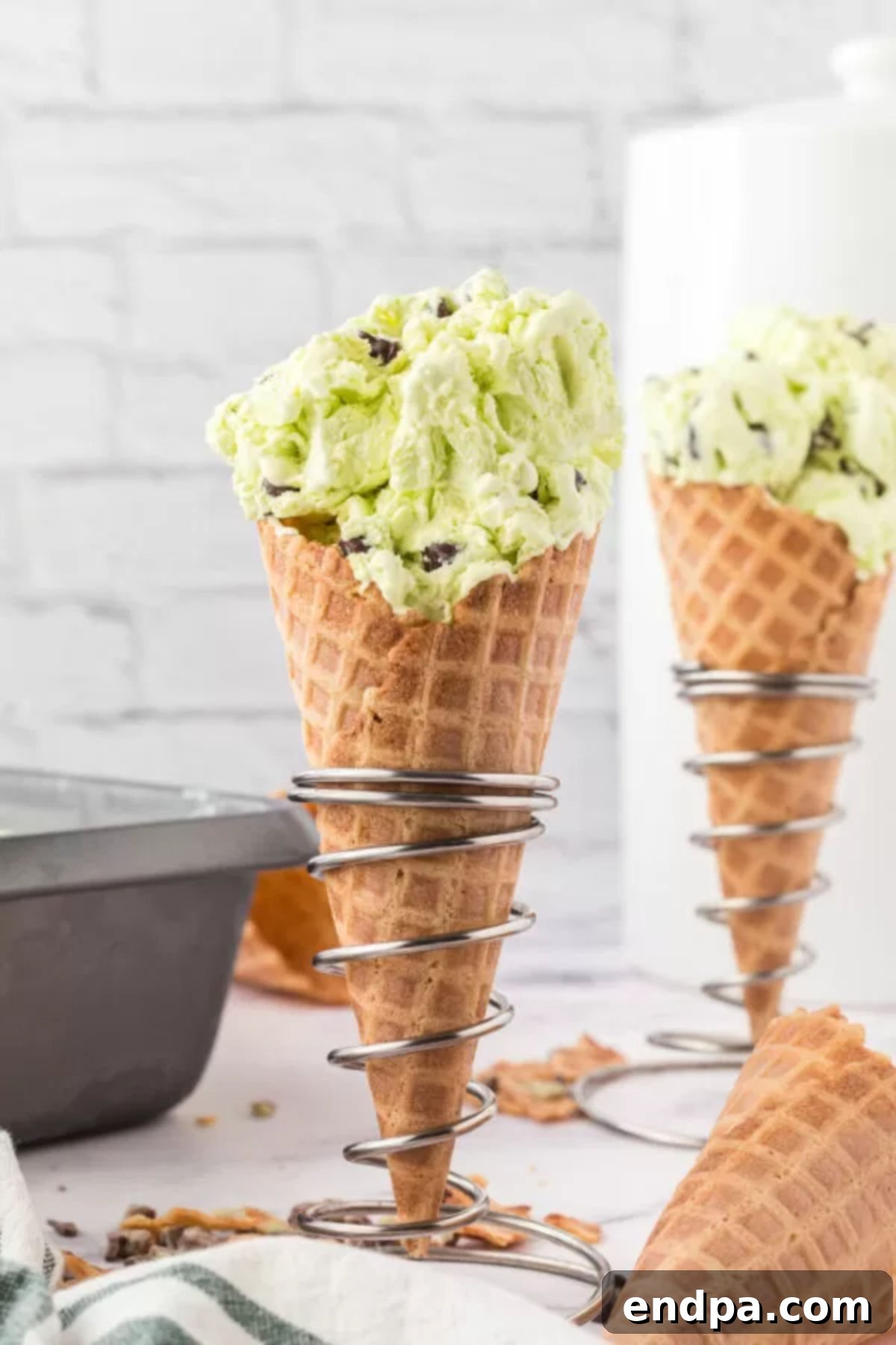 Mint chocolate chip ice cream in a cone, held by hand.