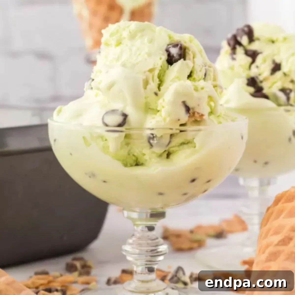Scoops of mint chocolate chip ice cream in a waffle cone.
