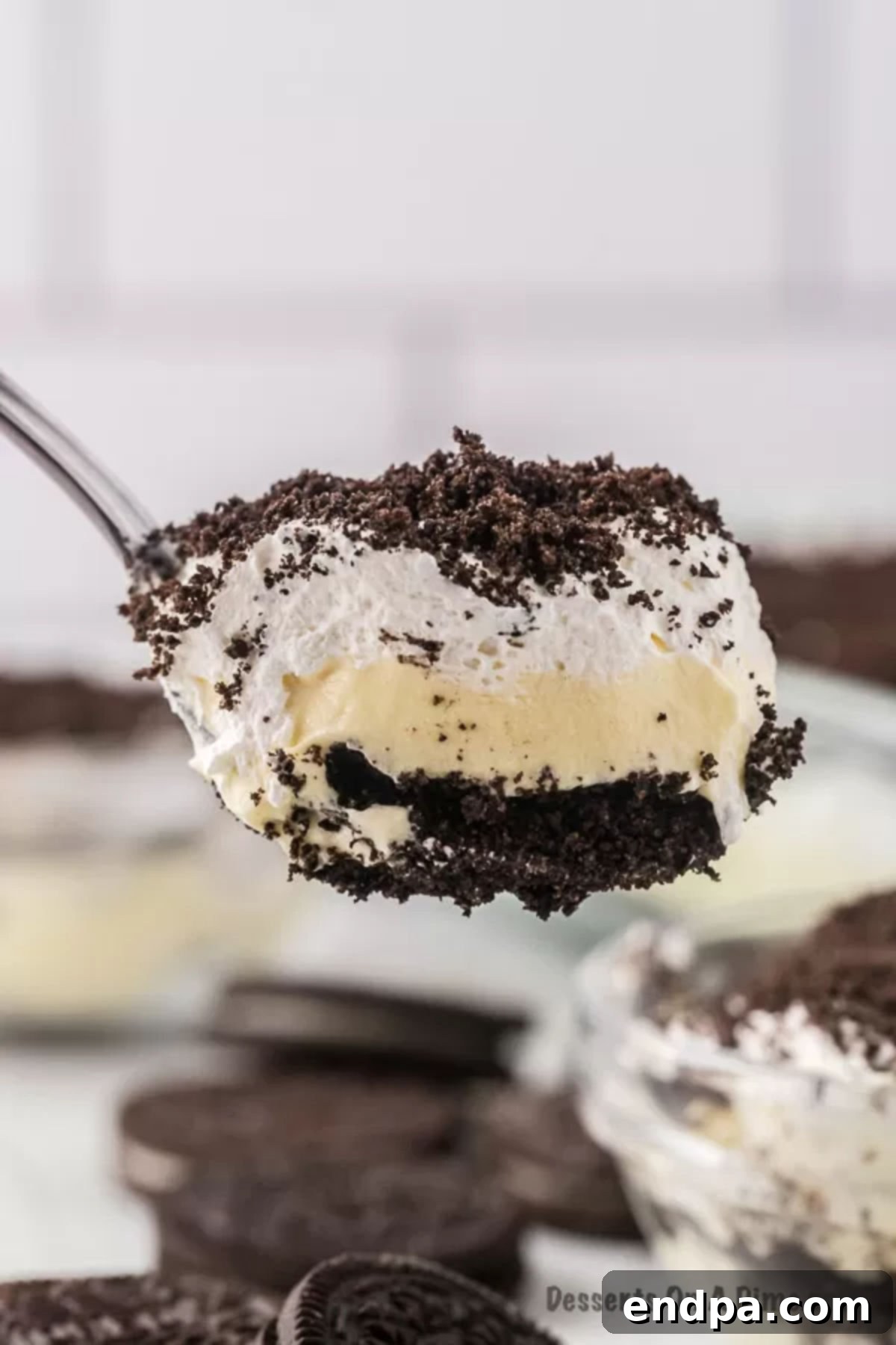 A close-up shot of a scoop of creamy Dirt Cake, showing the distinct layers of crushed Oreos and vanilla pudding filling, ready to be enjoyed.