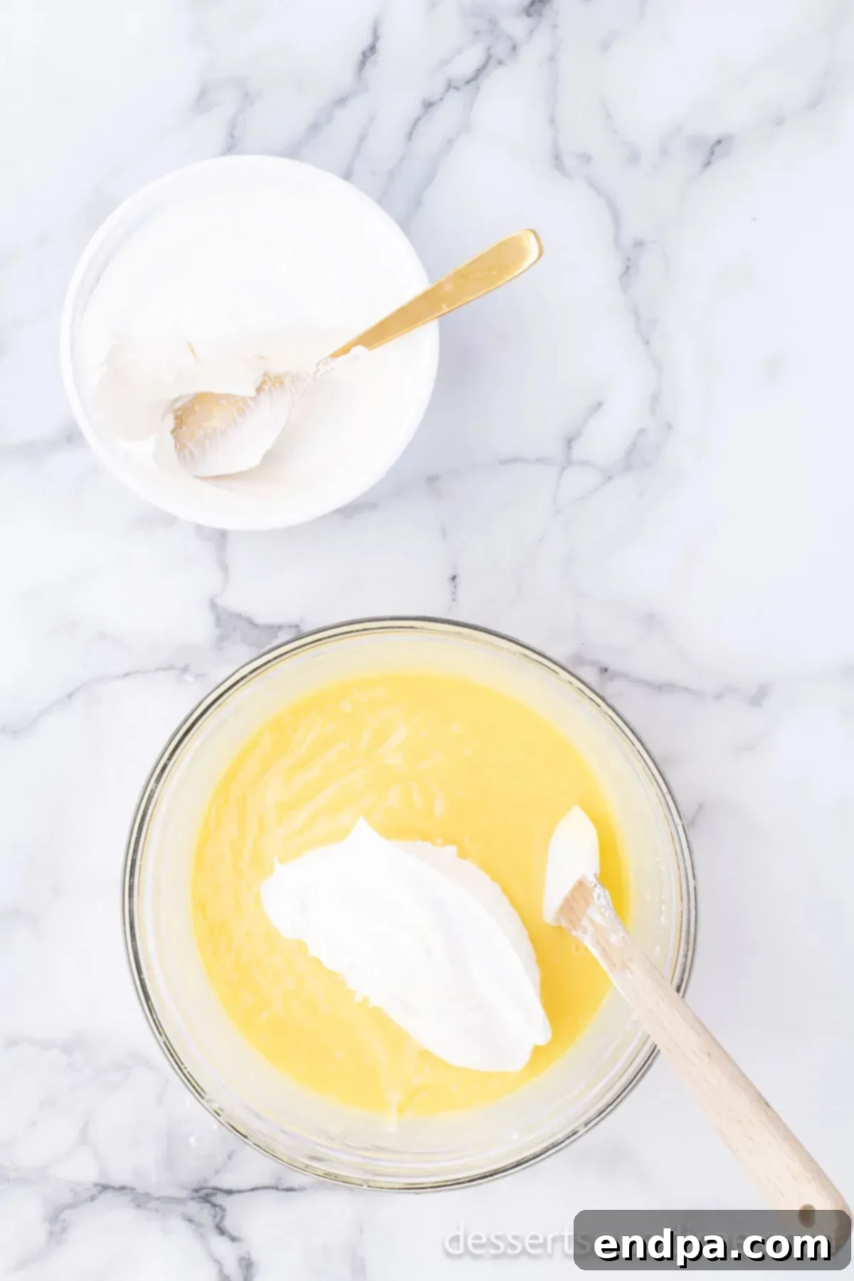 Thickened pudding mixture in a bowl, with whipped topping being folded in to create the creamy filling.