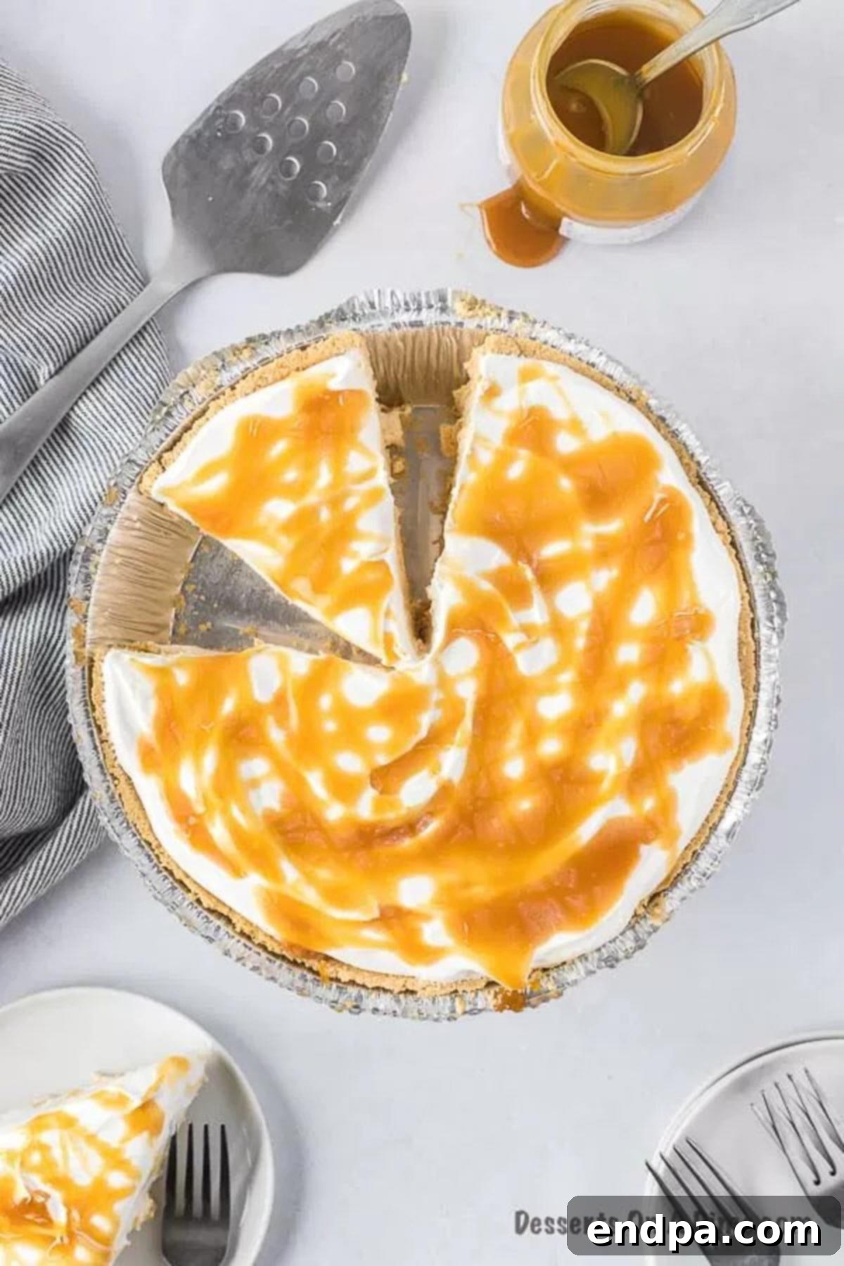 A perfectly sliced no-bake salted caramel pie, revealing its creamy layers and a rich caramel drizzle on top.