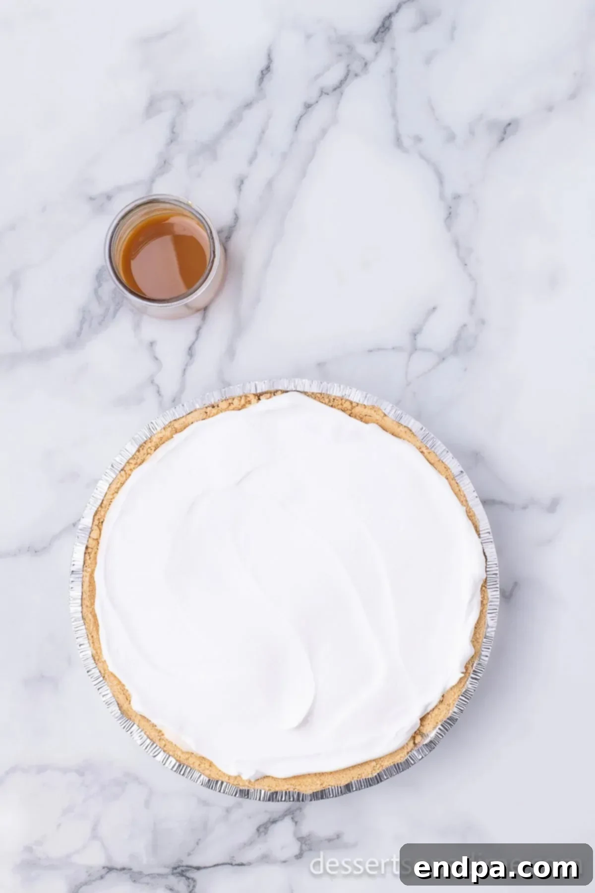The remaining whipped topping being spread generously over the top of the chilled no-bake salted caramel pie.