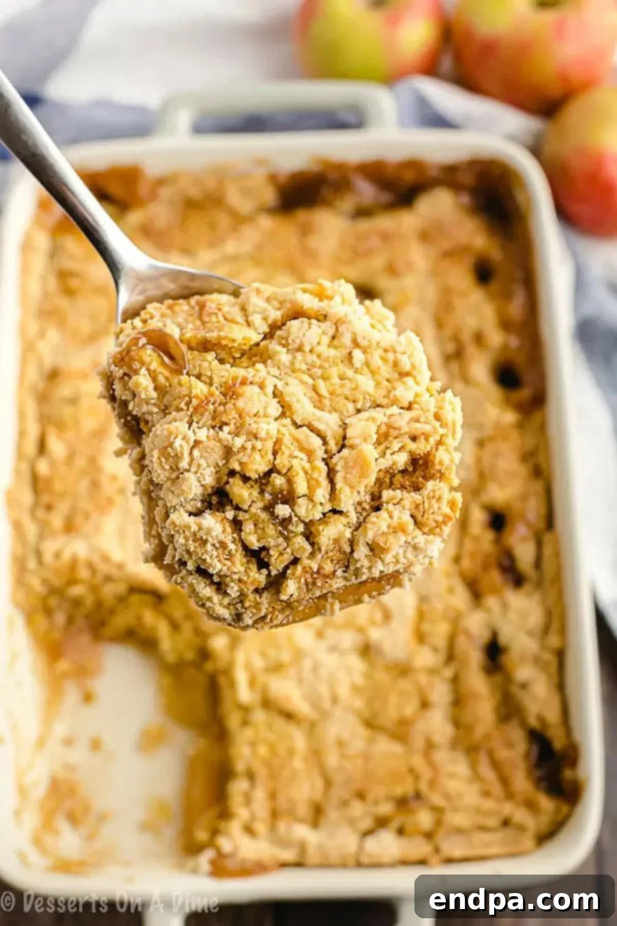 A spatula scooping a warm, gooey portion of caramel apple dump cake from a baking dish, showcasing the rich layers.