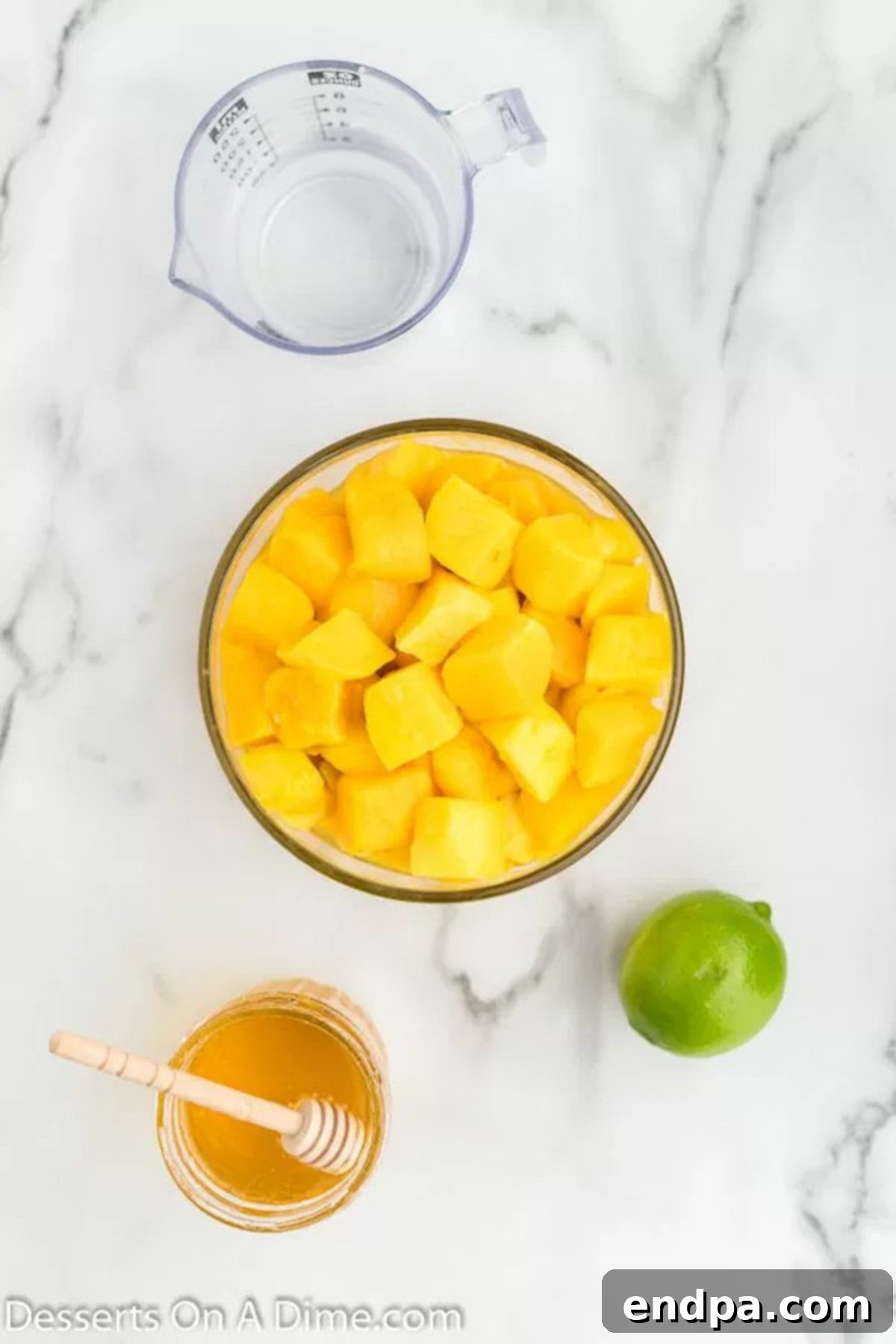 A vibrant display of fresh ingredients for mango popsicles: ripe mango cubes, golden honey, and bright green lime wedges, all arranged artfully.