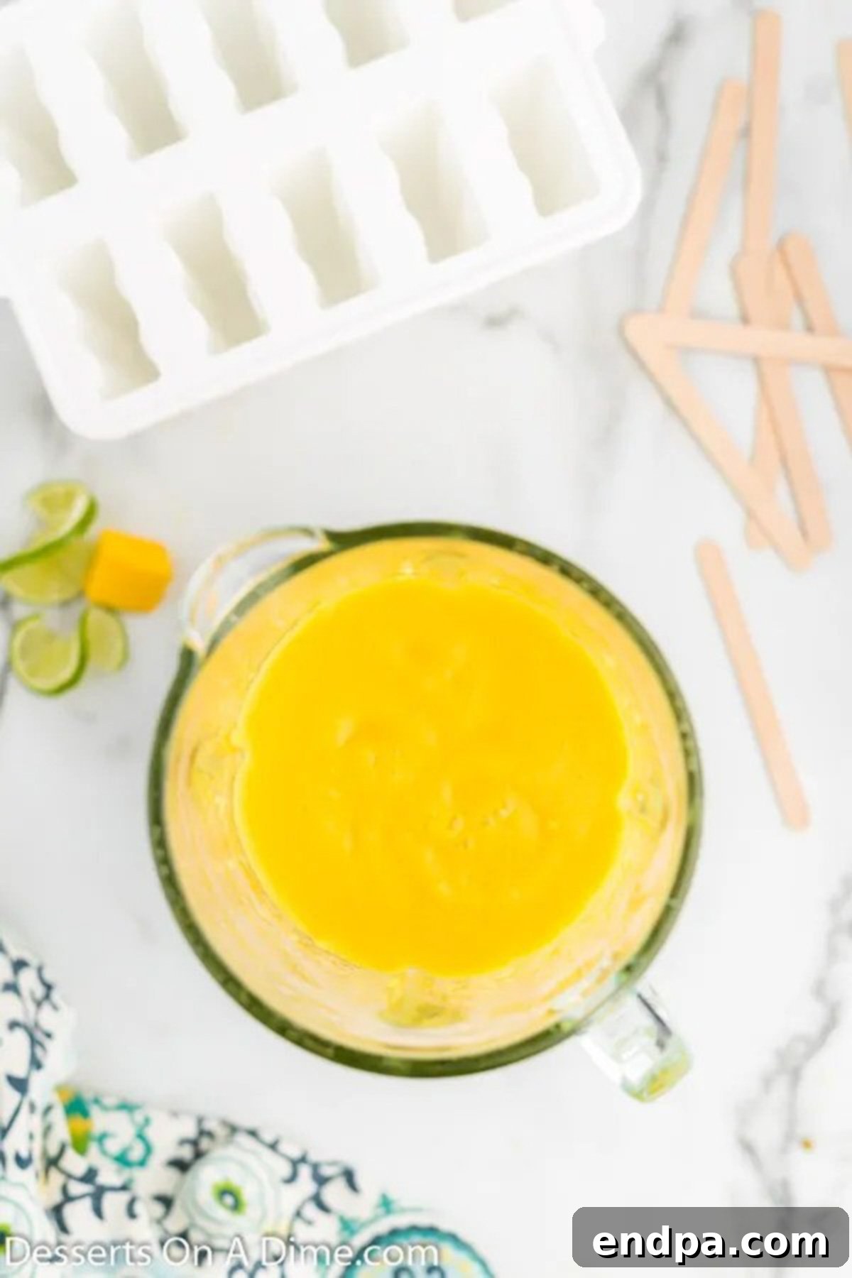 Close-up view of fresh mango chunks, honey, and lime juice being blended into a smooth, vibrant yellow puree in a food processor.