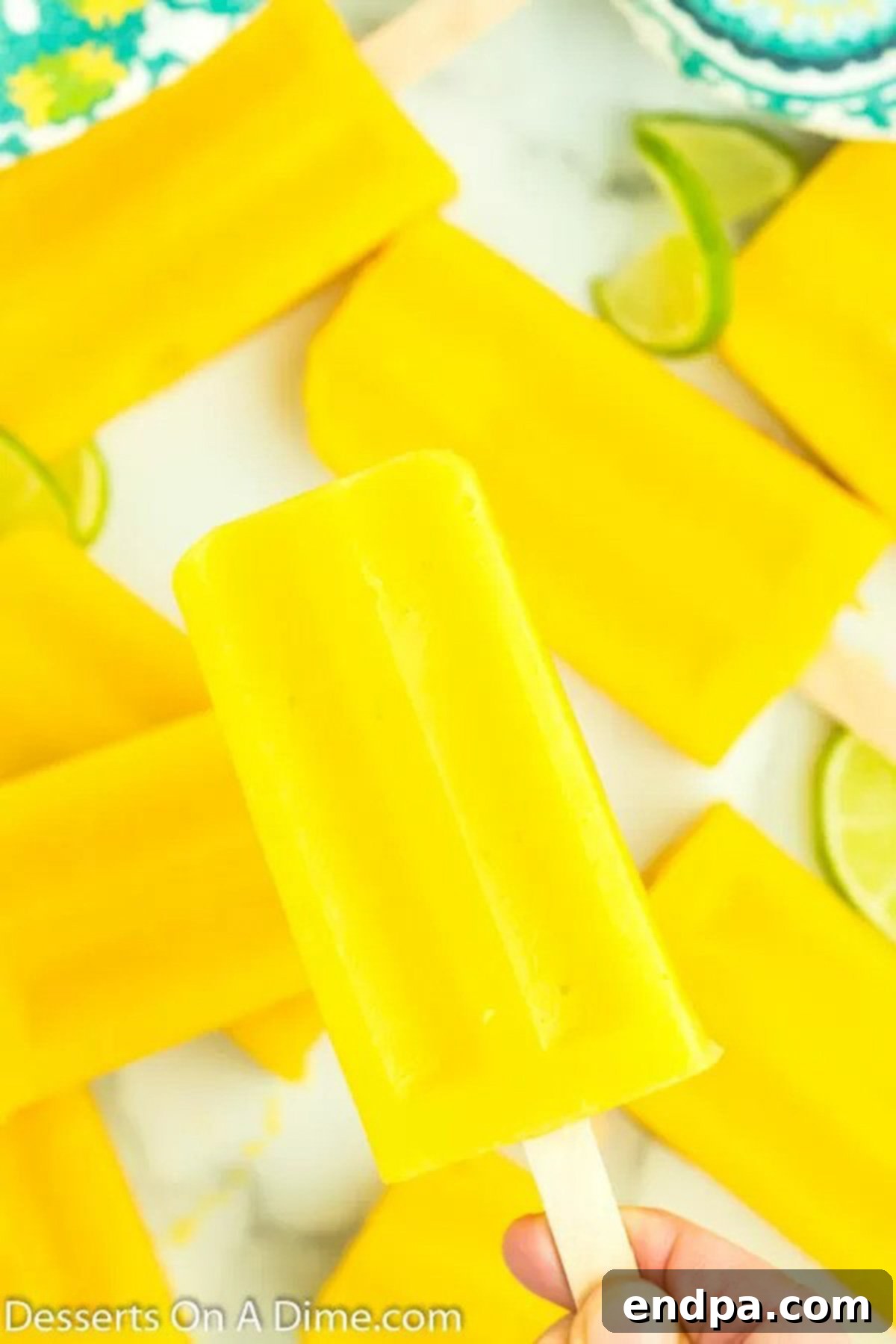 A close-up shot of two perfectly formed mango popsicles, vibrant yellow and inviting, placed on a light-colored tray.