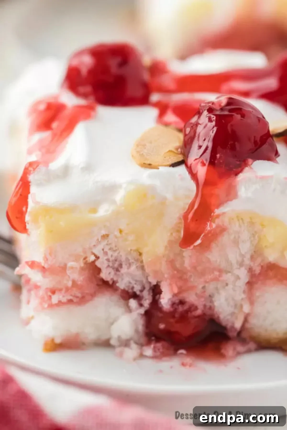 A close-up view of a perfectly chilled slice of Heaven on Earth Cake, adorned with toasted almond slivers, ready for a delightful bite.