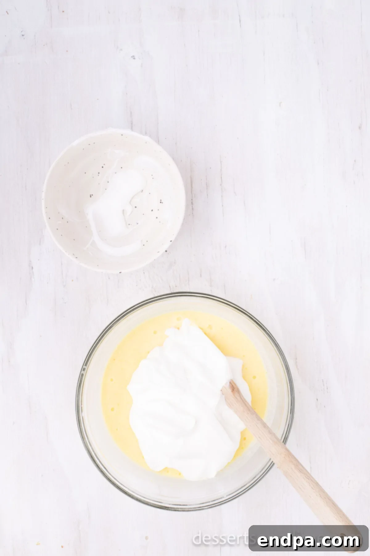 A mixing bowl containing instant vanilla pudding mix, milk, and sour cream, whisked until smooth.