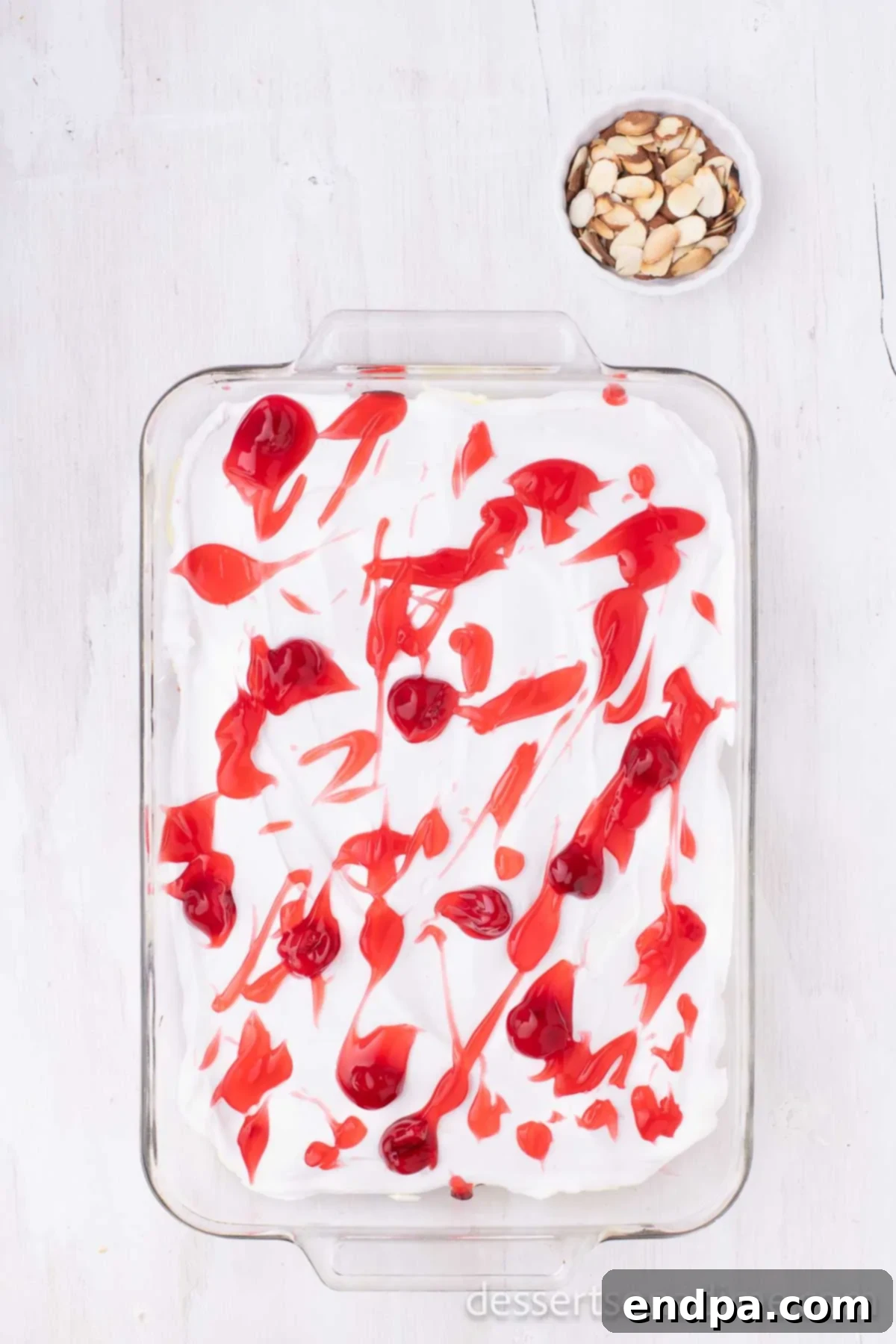 The remaining cherry pie filling artfully spread and swirled over the whipped cream topping, creating a decorative and delicious final layer.