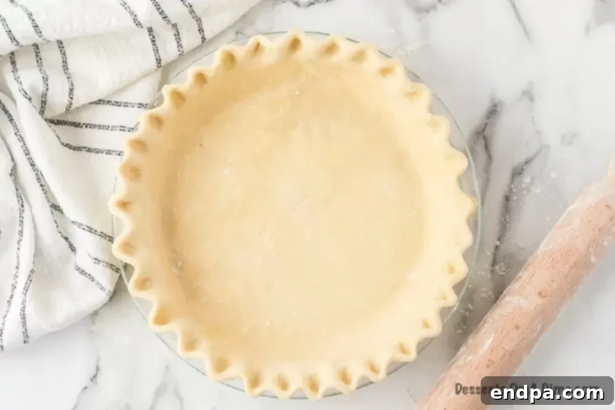 A freshly made pie crust sitting in a pie plate, ready to be filled and baked. The golden-brown edges are perfectly crimped.