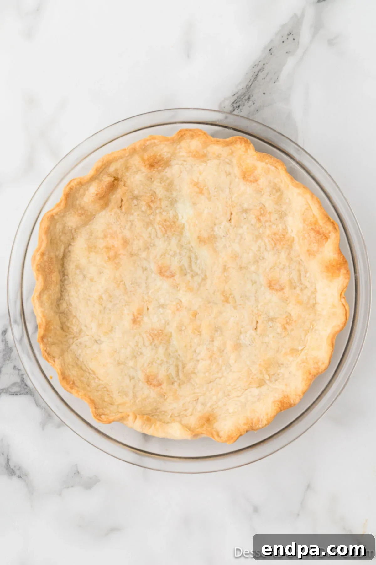 A golden brown, perfectly baked pie crust, showcasing its inviting flaky texture, freshly removed from the oven.