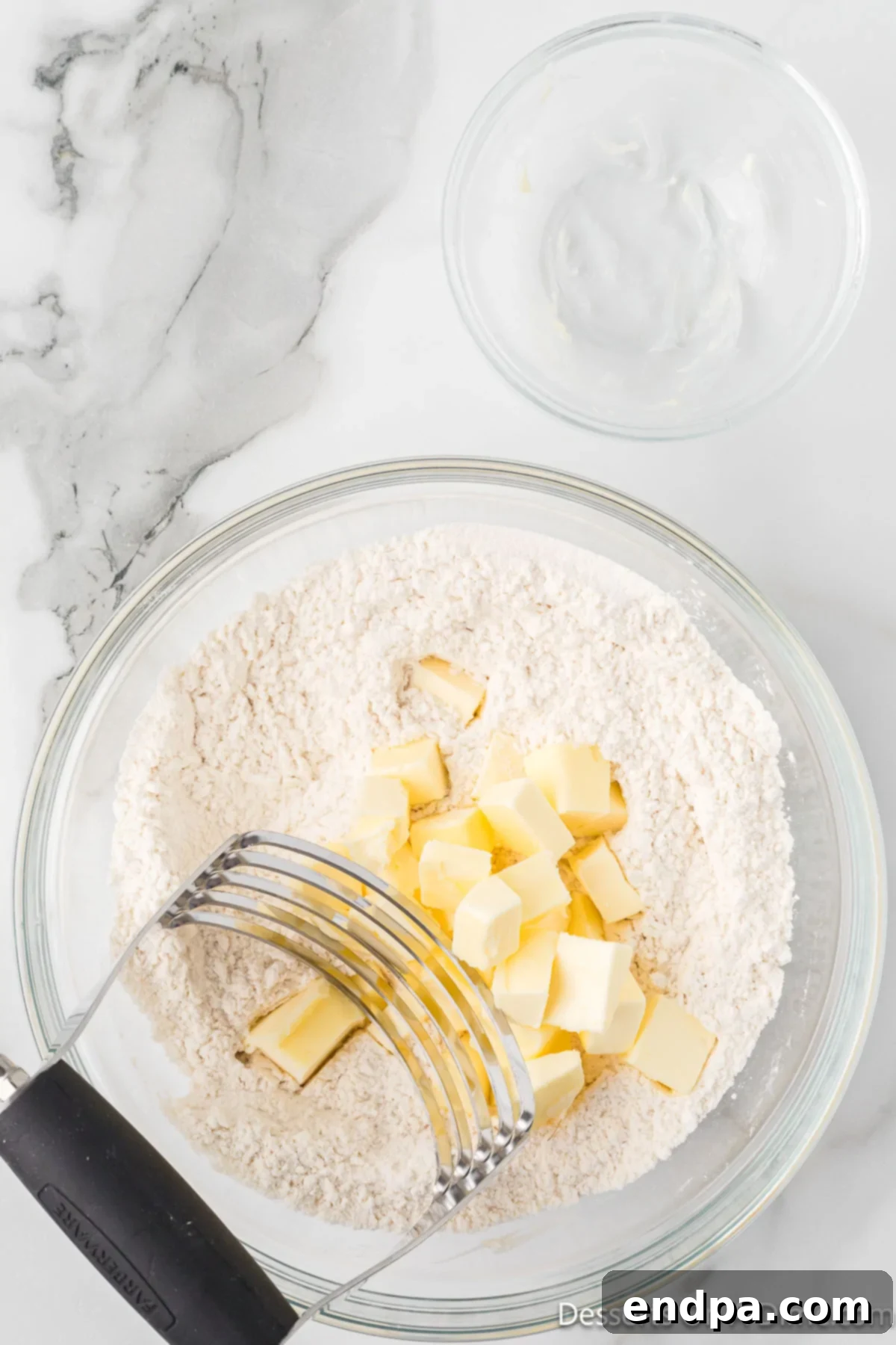 Precisely diced cold butter being added to the flour and salt mixture in a bowl.