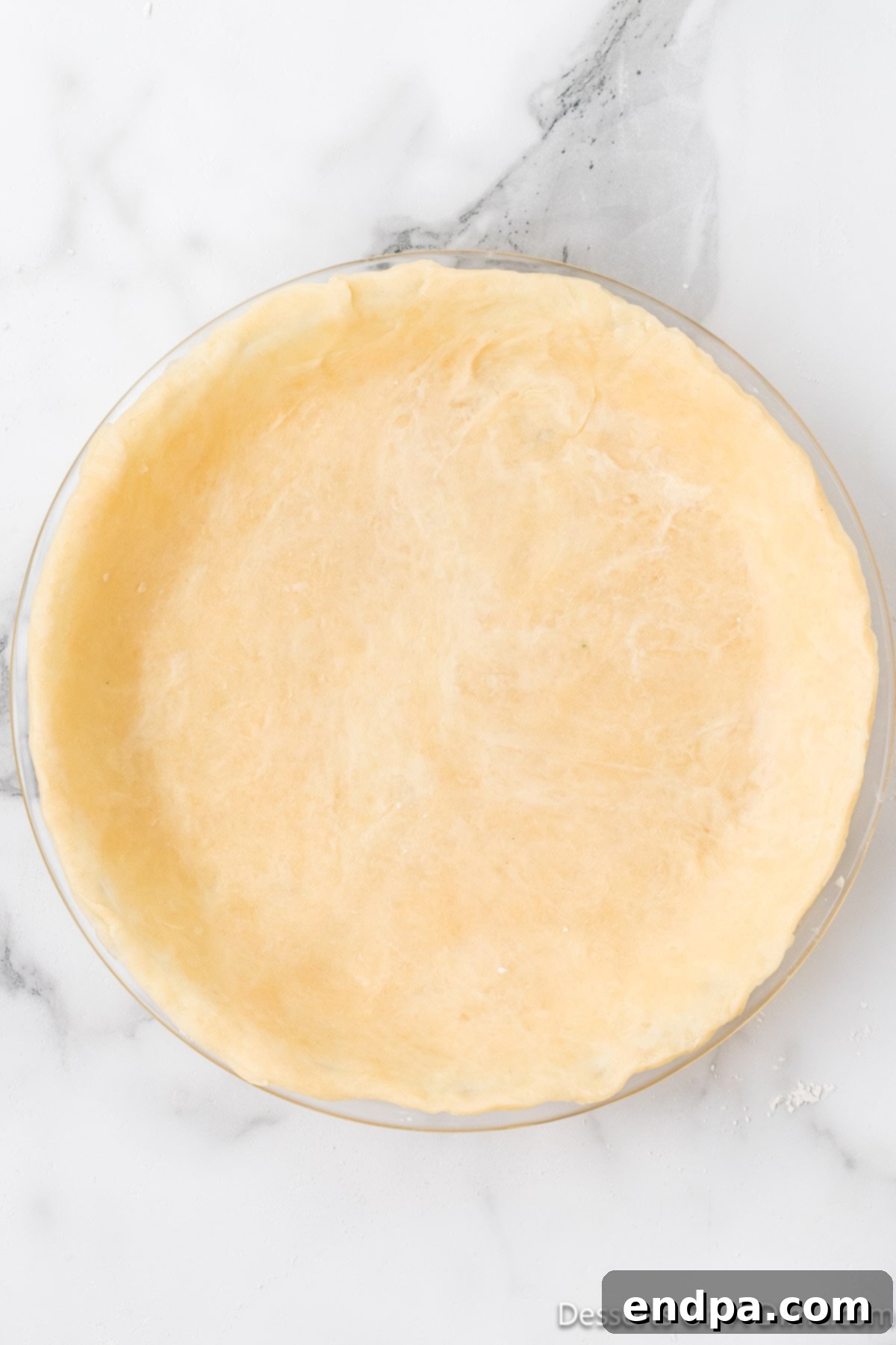 The delicately rolled-out pie dough being meticulously placed into a pie plate.