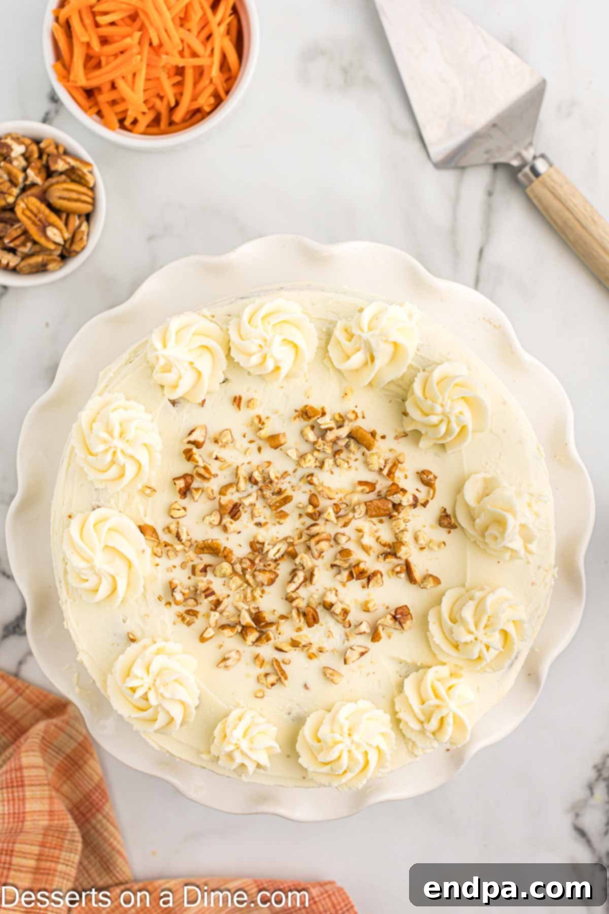 Close-up of a frosted keto carrot cake, beautifully decorated with chopped pecans on top.