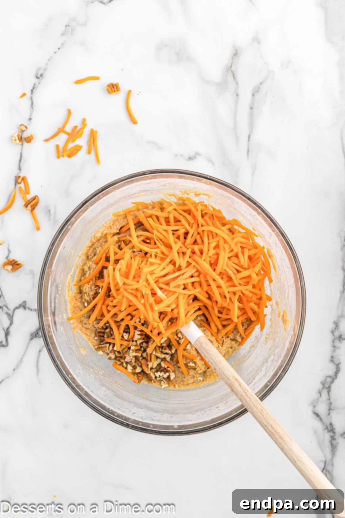 Freshly shredded carrots and chopped pecans being folded into the cake batter.