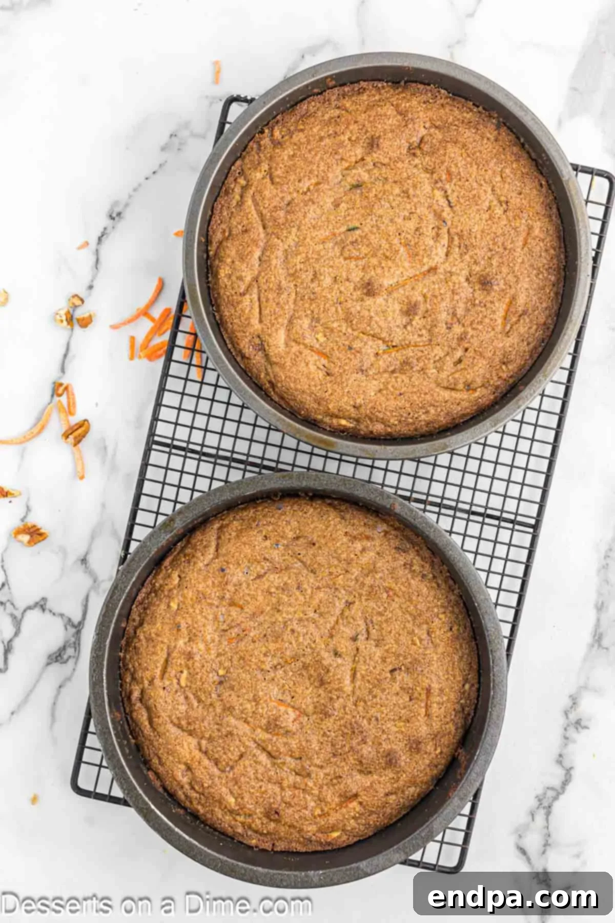Baked carrot cake layers cooling in their pans on a wire rack.