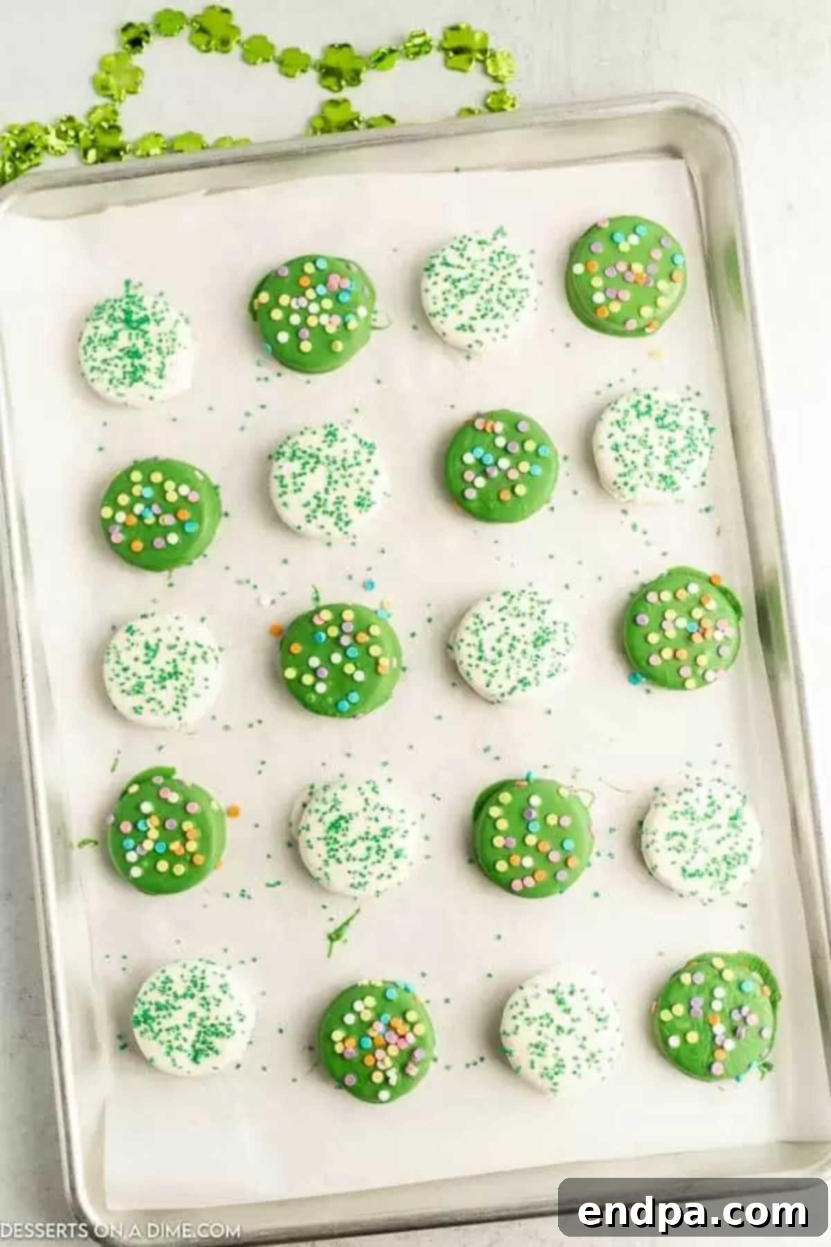 Pot O' Gold Chocolate Oreos 5 Oreo cookies topped with festive sprinkles on a baking sheet, freshly dipped.