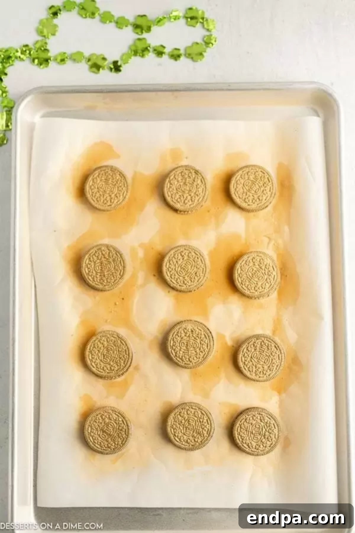 Freshly sprayed gold Oreos drying on a baking sheet, gleaming with metallic luster.