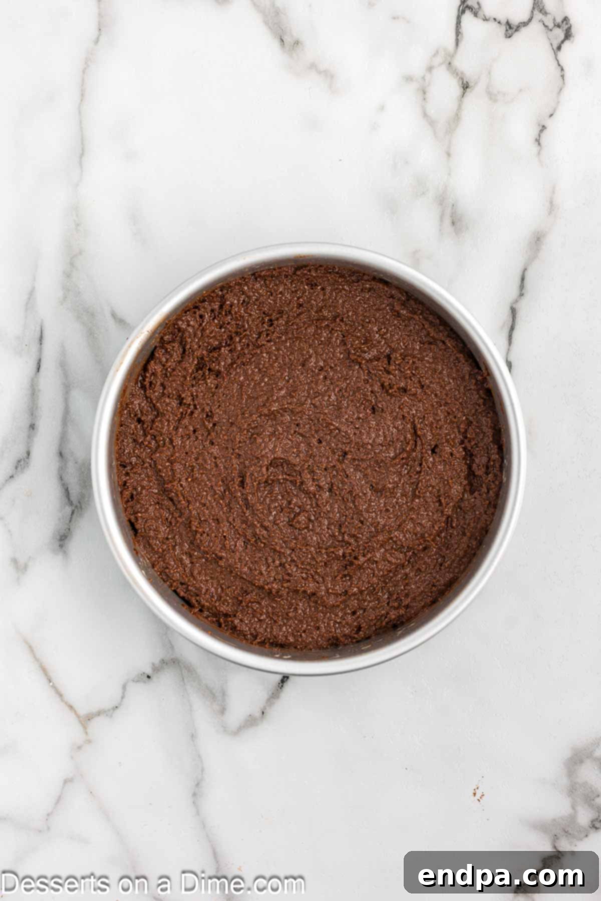 Decadent Keto Chocolate Dream 6 Smooth chocolate cake batter evenly spread in a round cake pan, perfectly prepared for baking to ensure a flat and even cake layer.