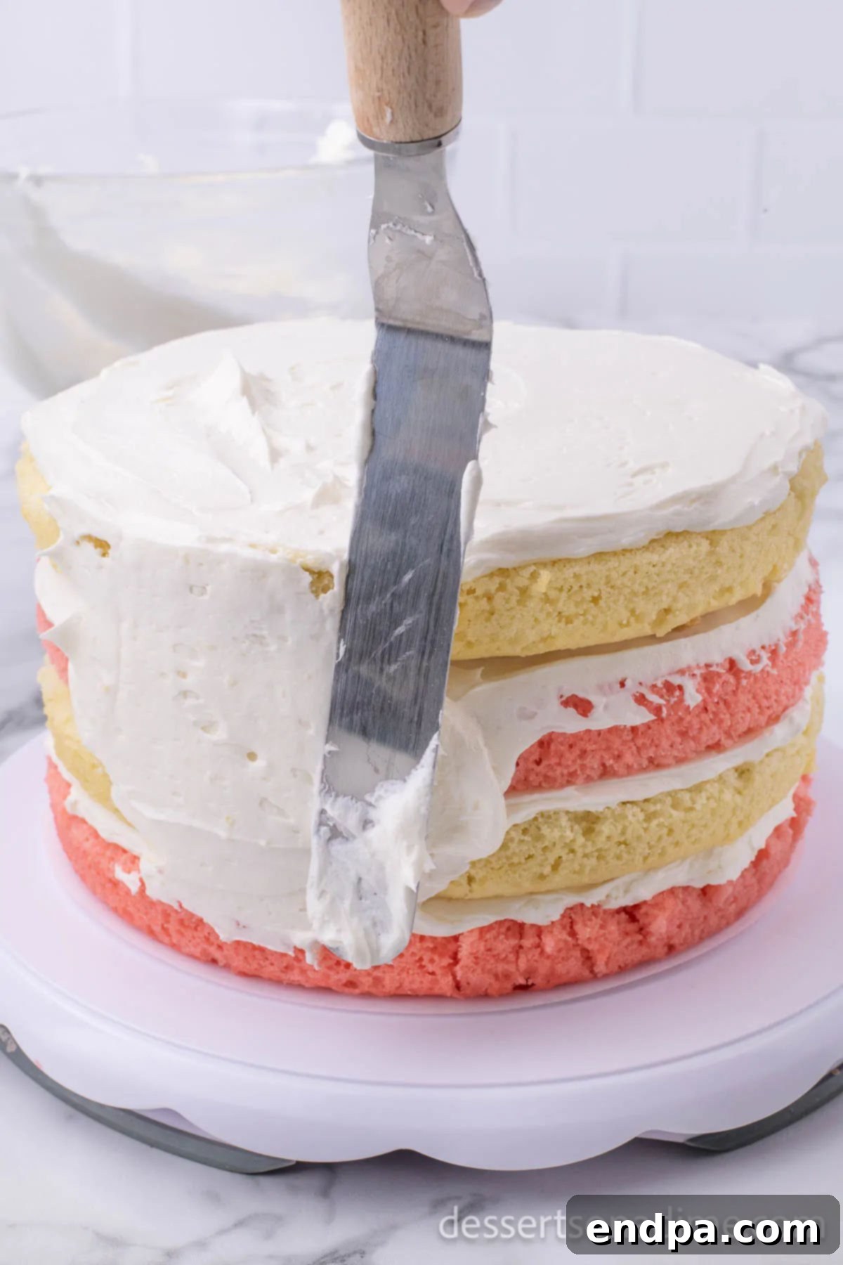 Frosting the sides of the cake with an offset spatula.