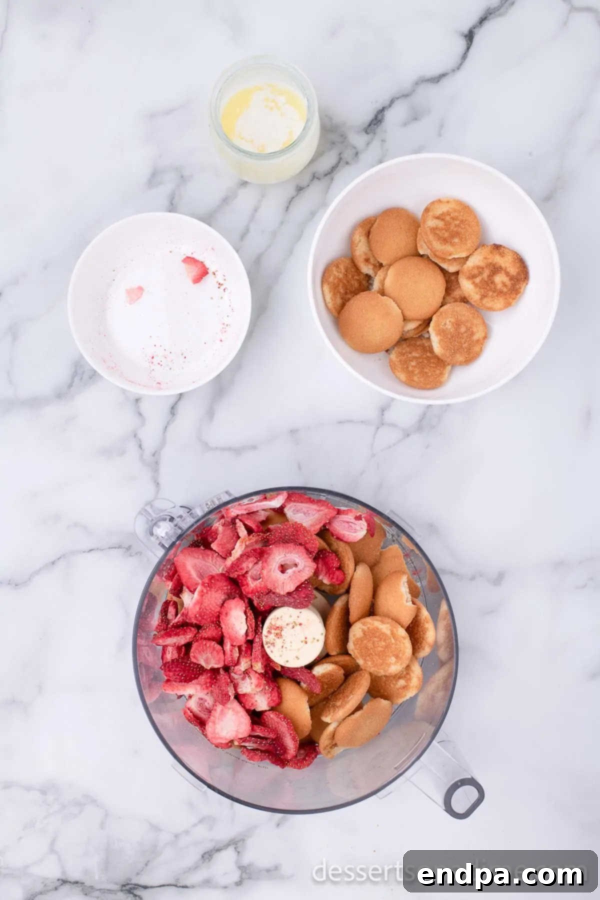 Food processor containing freeze-dried strawberries and vanilla wafers, ready to be processed.