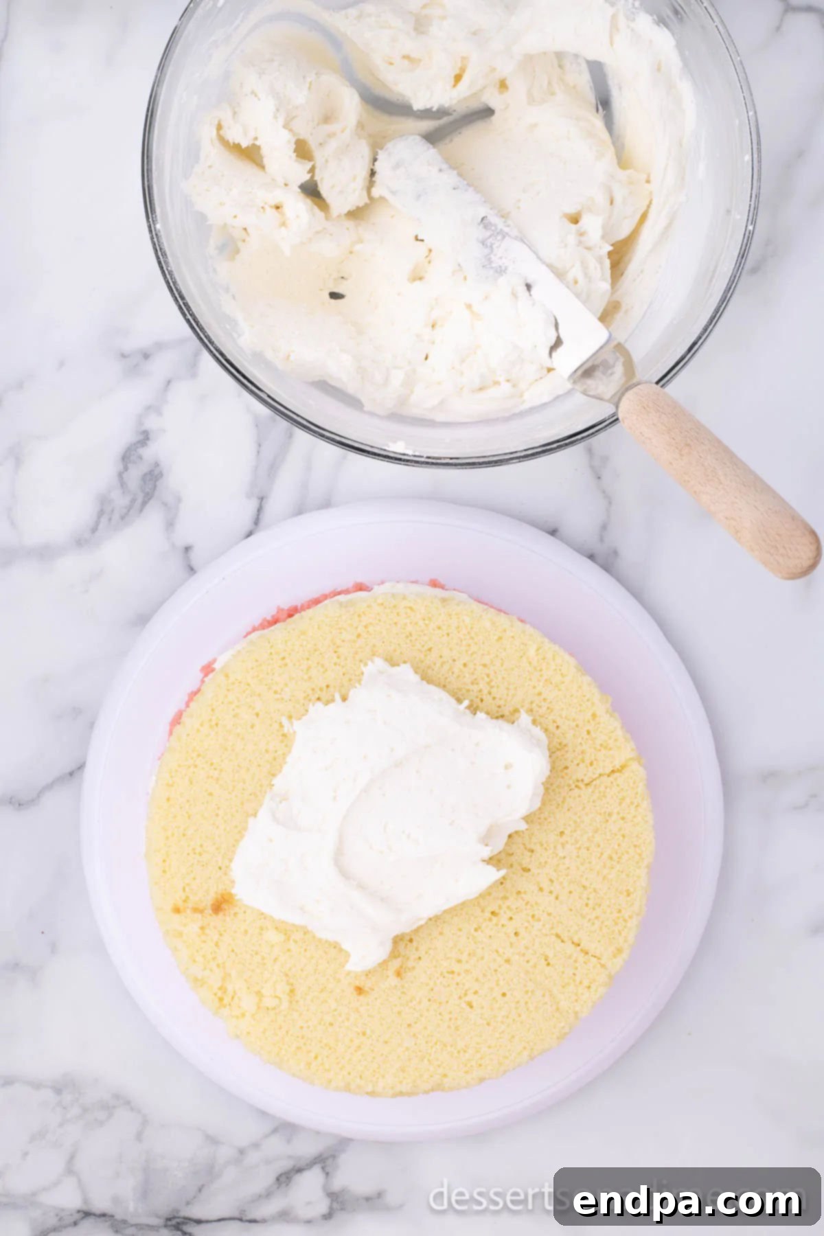White cake layer stacked on top of the frosted strawberry layer.