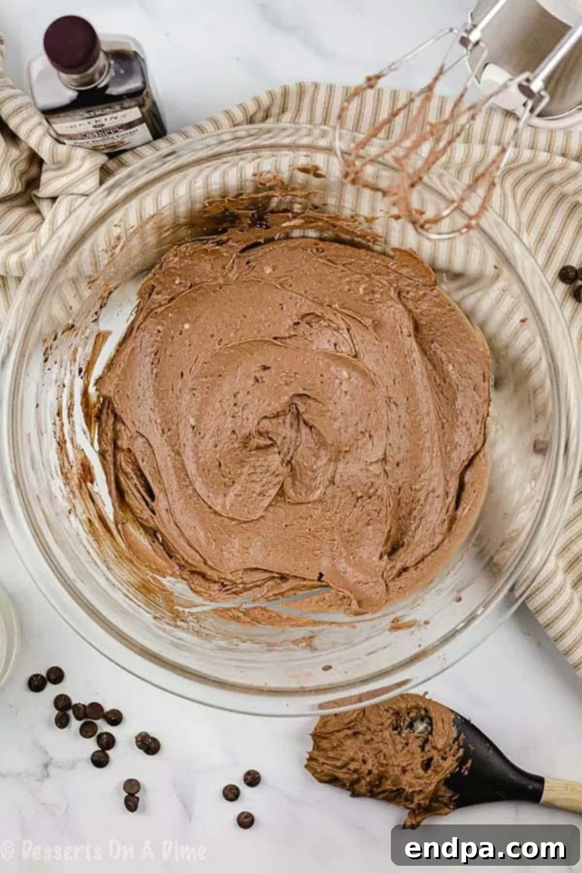 Close up image of a bowl of melted chocolate and coconut oil, forming a smooth, glossy liquid base for the frosting.